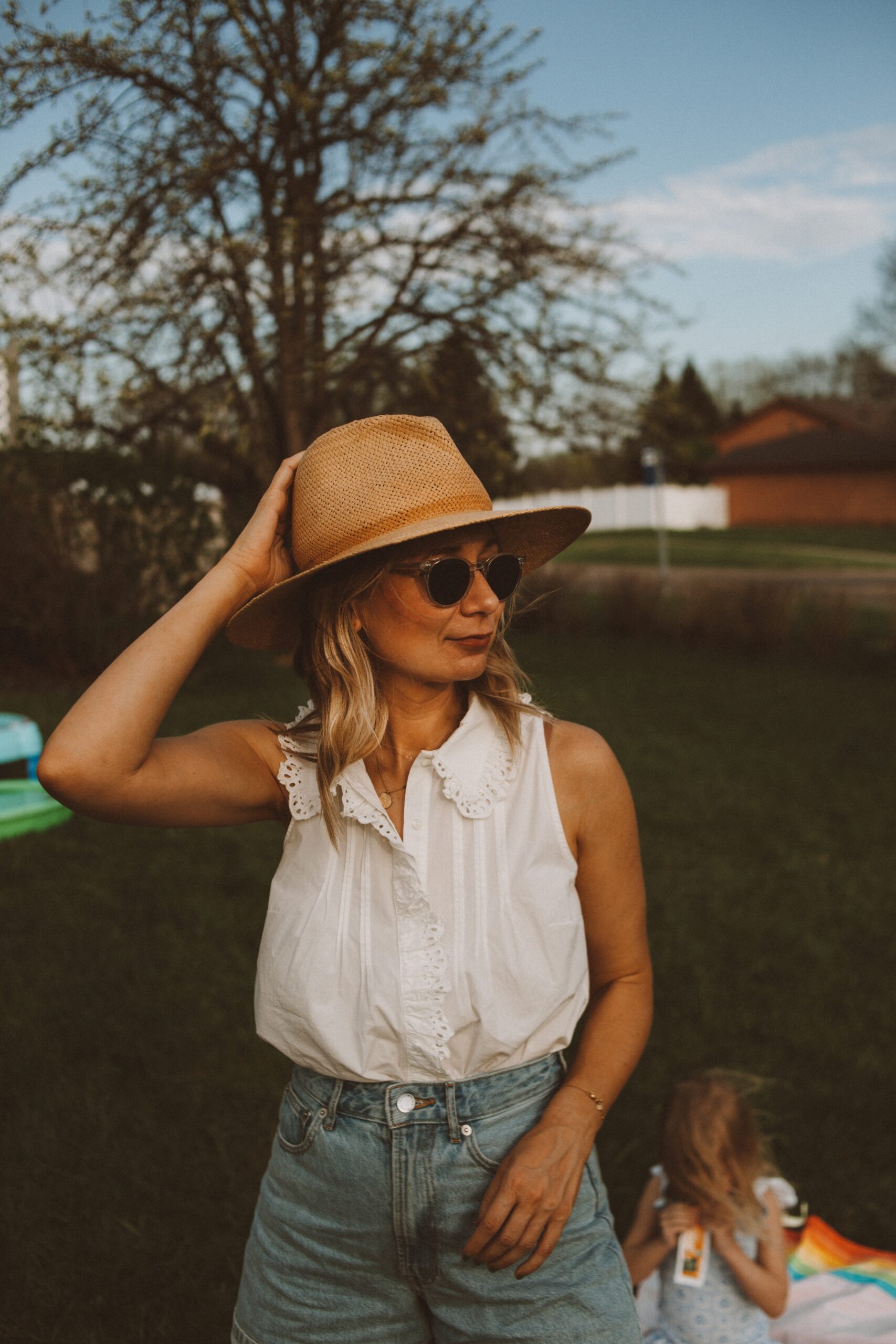 Karin Emily wears white tops from Sezane with a pair of Everlane denim shorts, and a janessa leone hat