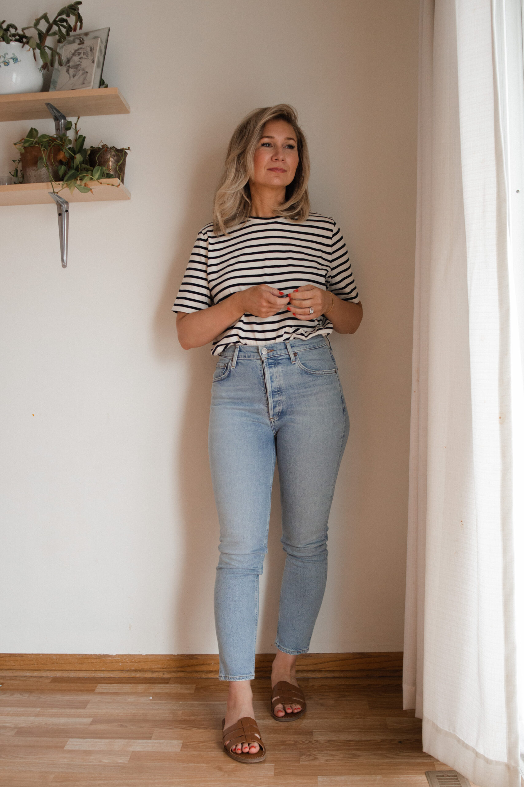 Karin Emily wears a pair of AGOLDE Nico jeans with a striped tee and brown sandals for her AGOLDE denim guide