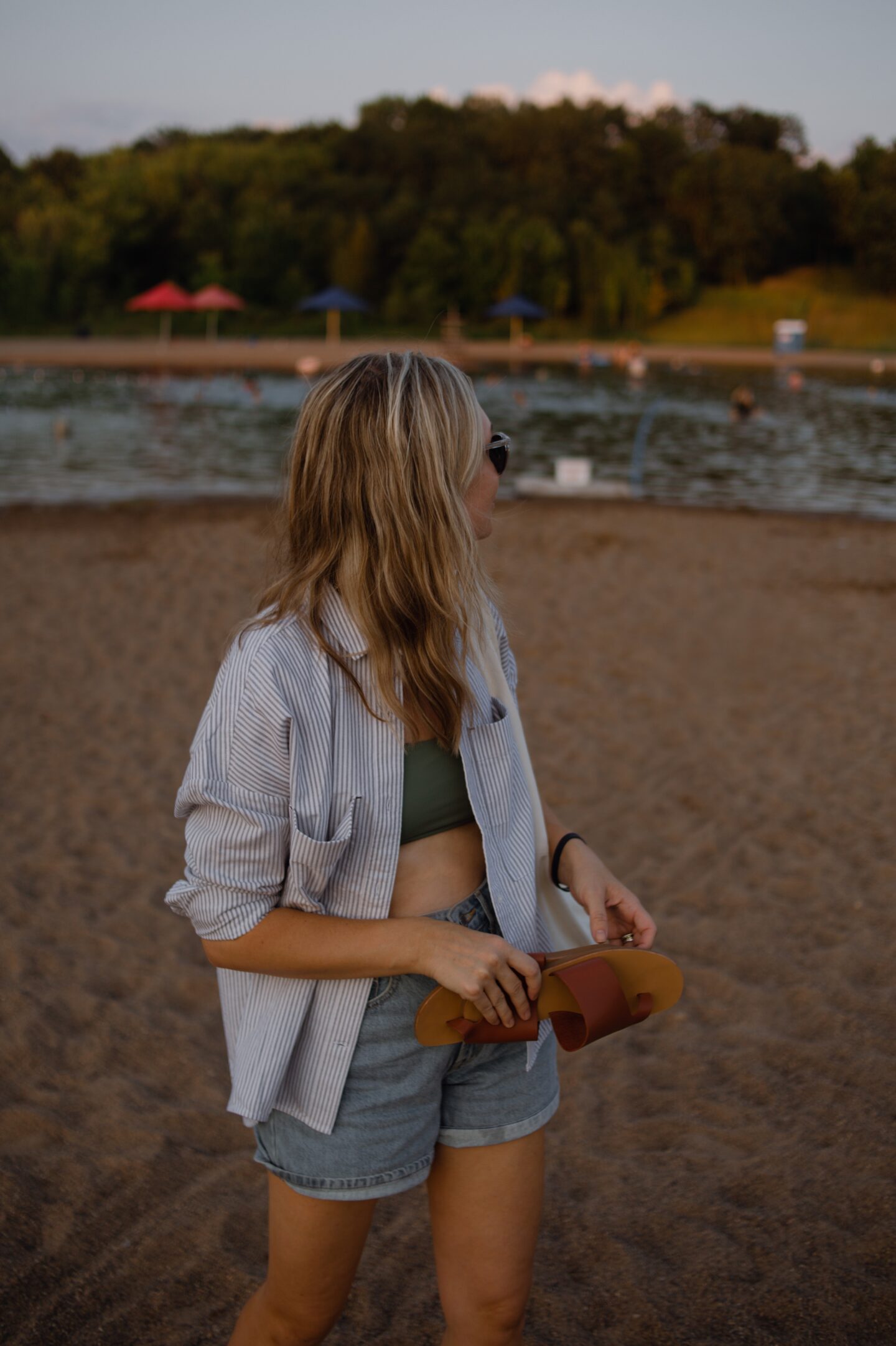 Karin Emily wears her Everlane favorites: a striped button down over a green bikini top and vintage inspired denim shorts