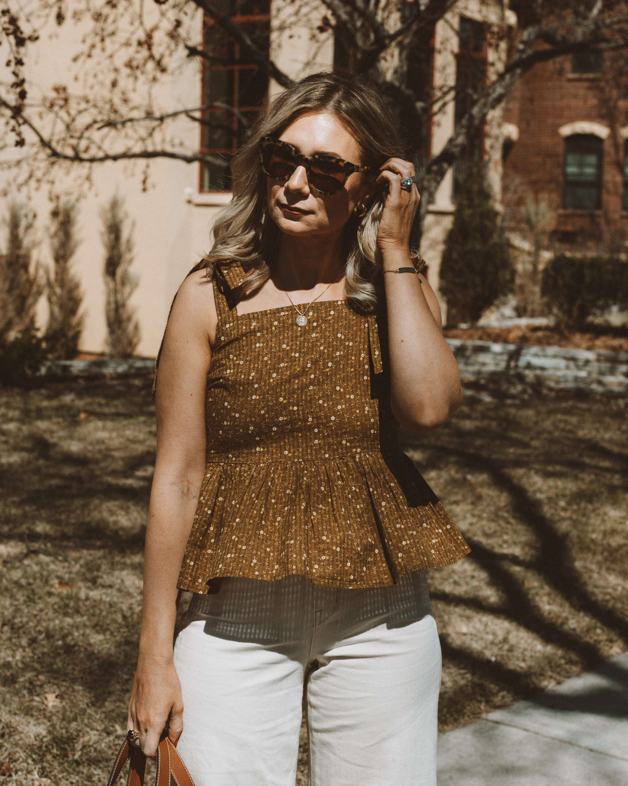 Karin Emily wears a peplum top from Madewell, J. Crew Cabana Sunglasses, and wide leg jeans from AYR