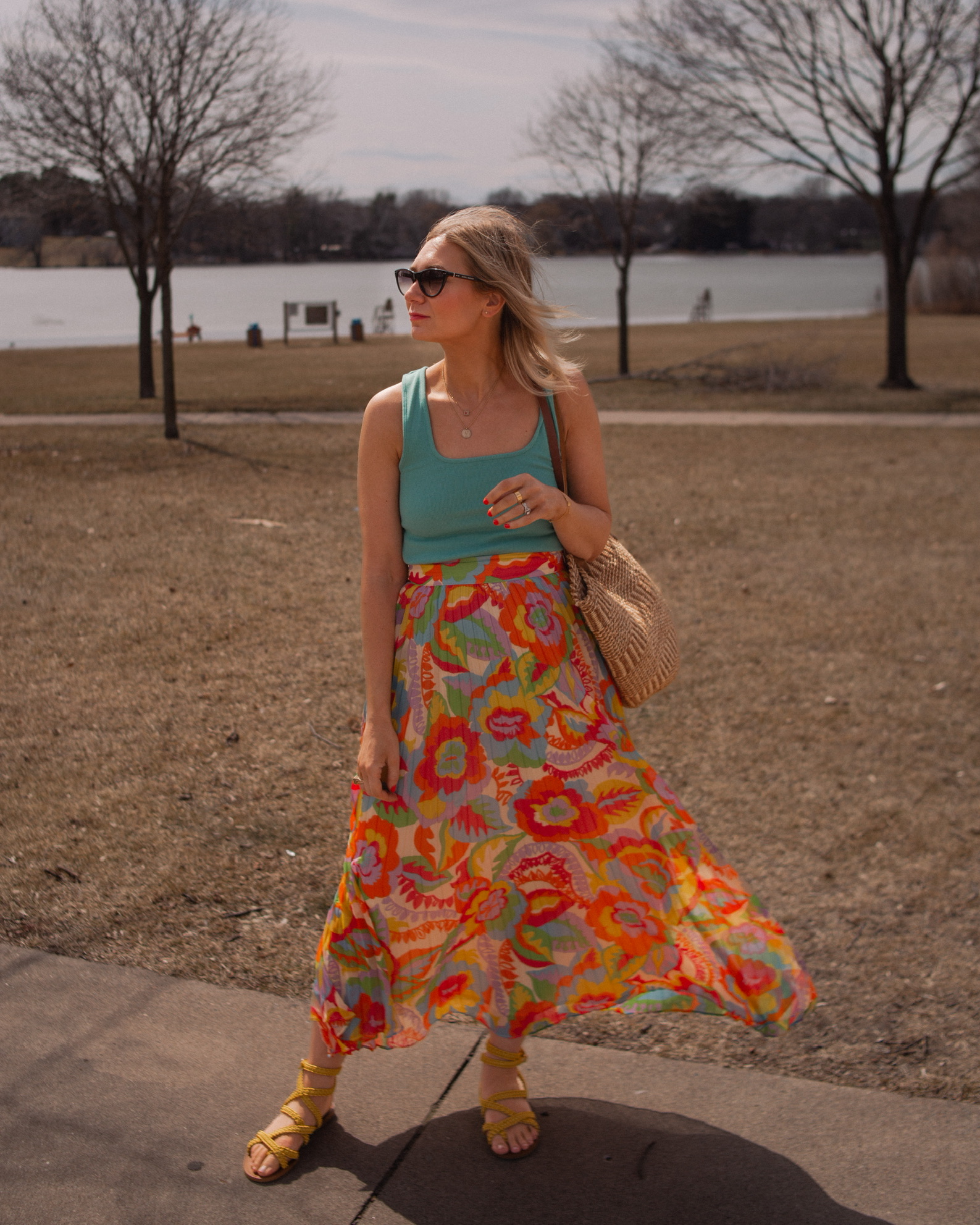 Karin Emily wears a turquoise juan t-shirt from Sezane with A brightly colored floral maxi skirt, yellow sandals,  and Isabel Marant Cat Eye Sunglasses