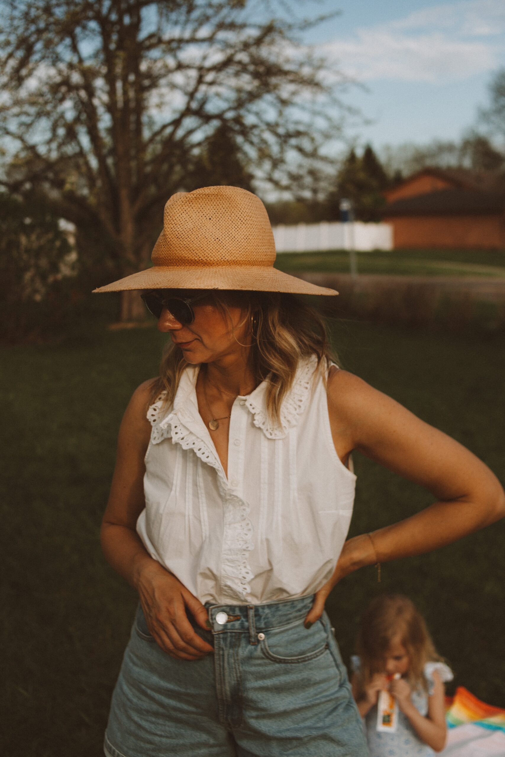 Karin Emily wears white tops from Sezane with a pair of Everlane denim shorts, and a janessa leone hat