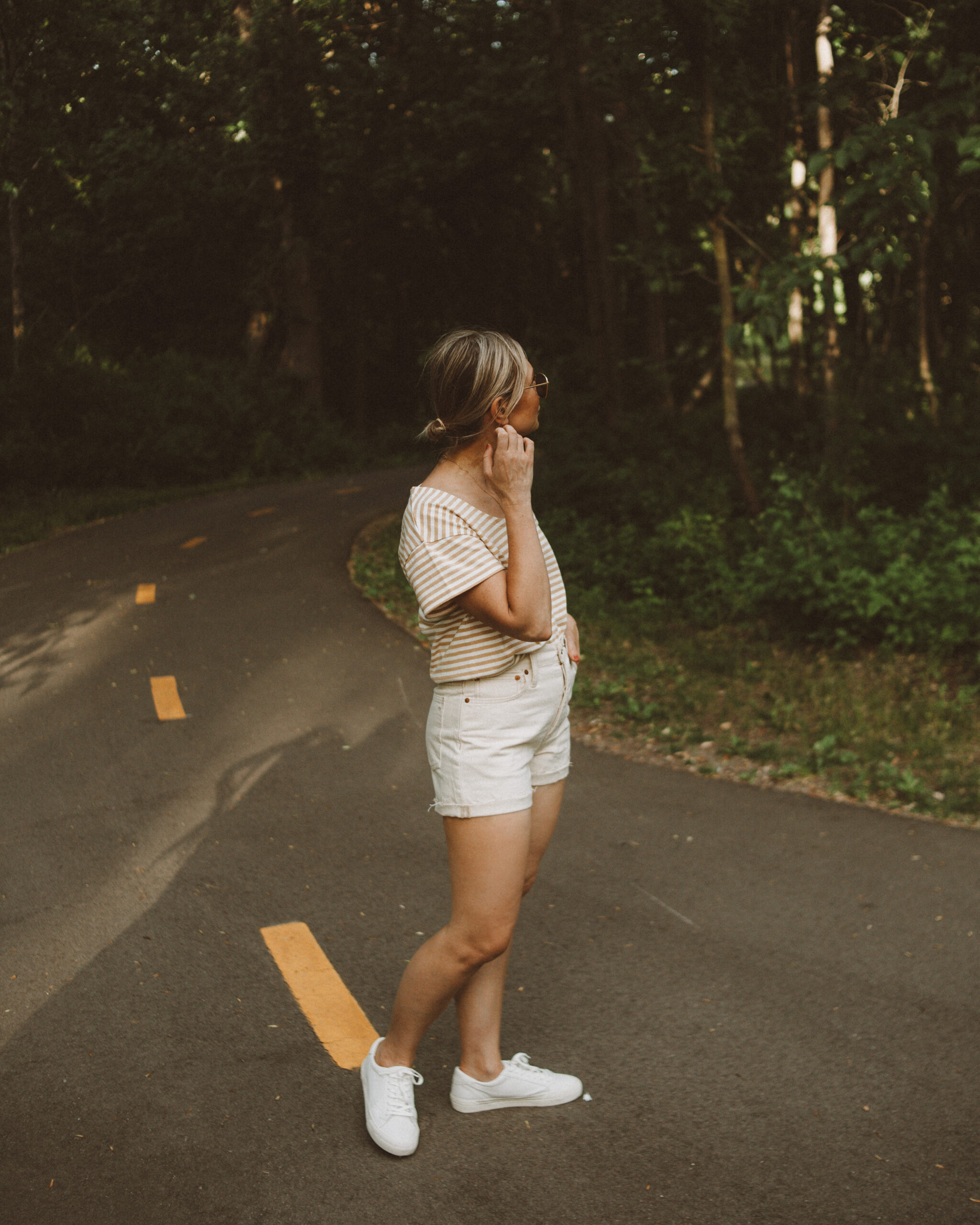 Karin Emily wears a striped tee, white sneakers, and cream jean shorts