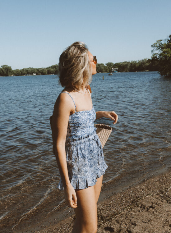 Karin Emily wears a blue and white one piece swimsuit with a pair of swim short coverups