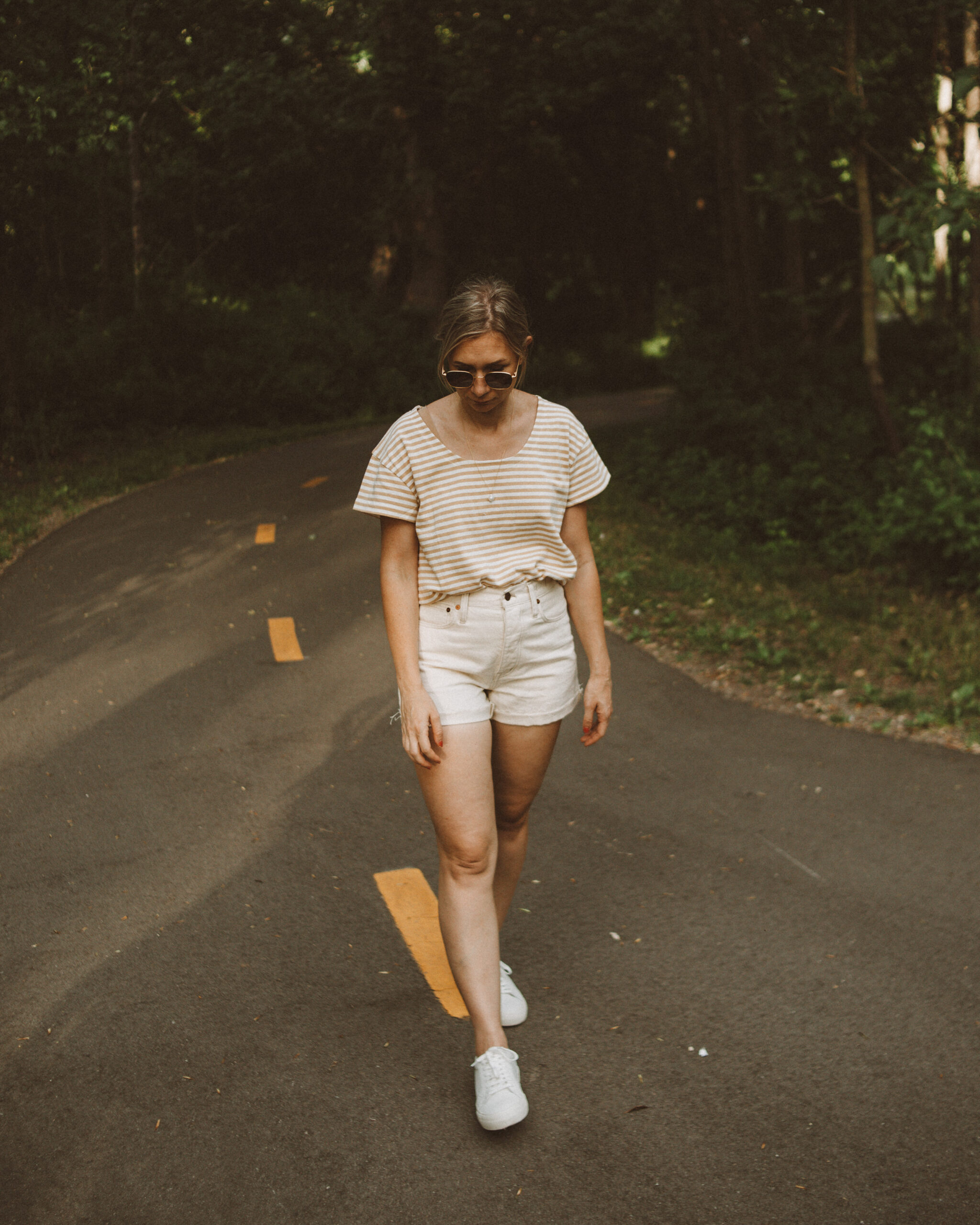 Karin Emily wears a striped tee, white sneakers, and cream jean shorts