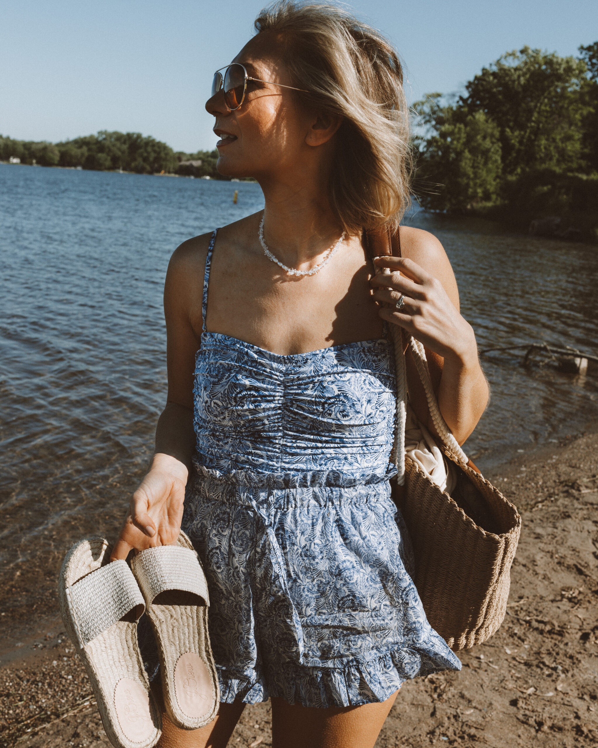 Karin Emily wears a blue and white one piece swimsuit with a pair of swim short coverups