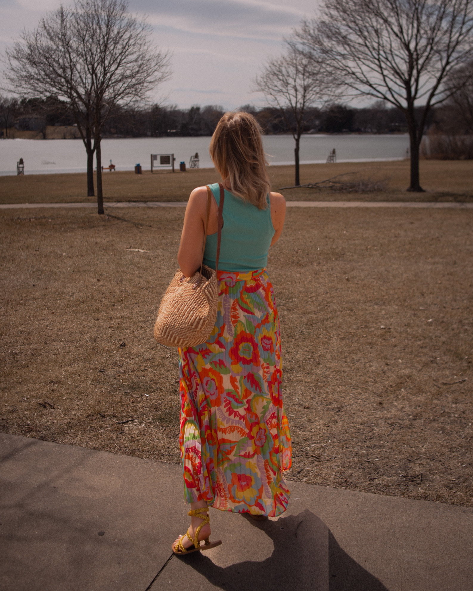 Karin Emily wears a turquoise tank top, floral skirt and yellow wrap sandals