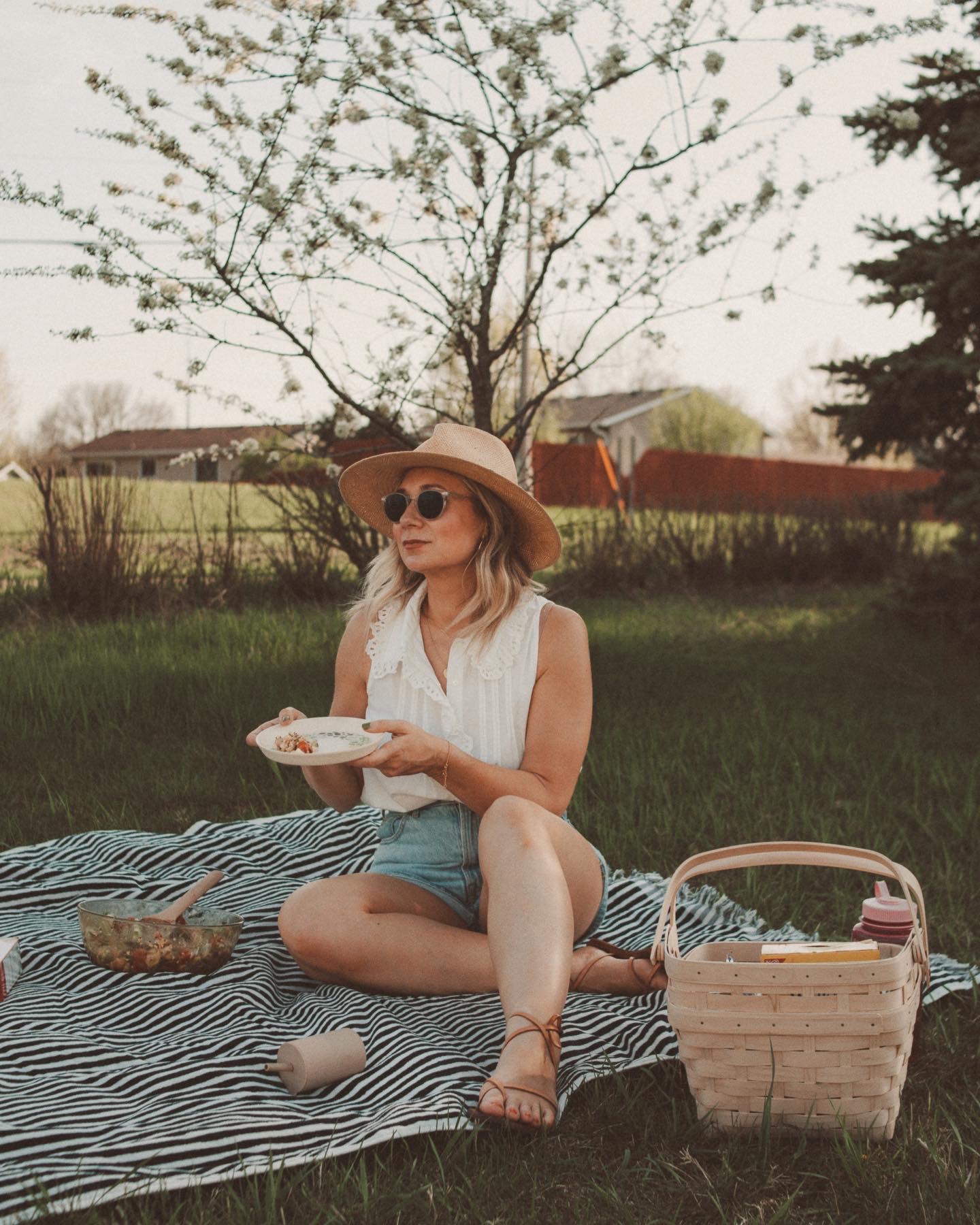 Karin Emily wears a white button down Sezane top, Everlane a line denim shorts, and brown strappy sandals