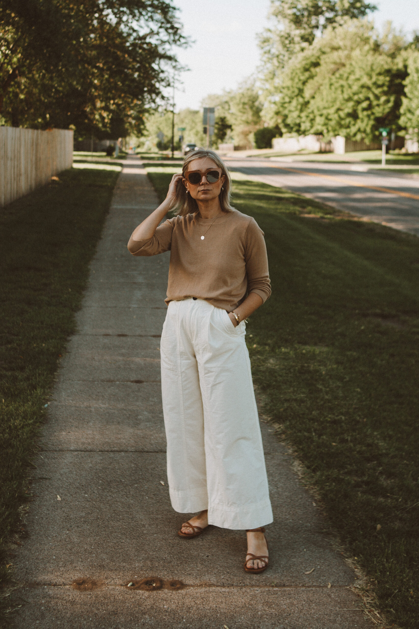 Karin Emily wears a camel sweater from It is Well L.A., white wide leg pants from Everlane and brown sandals from Margaux