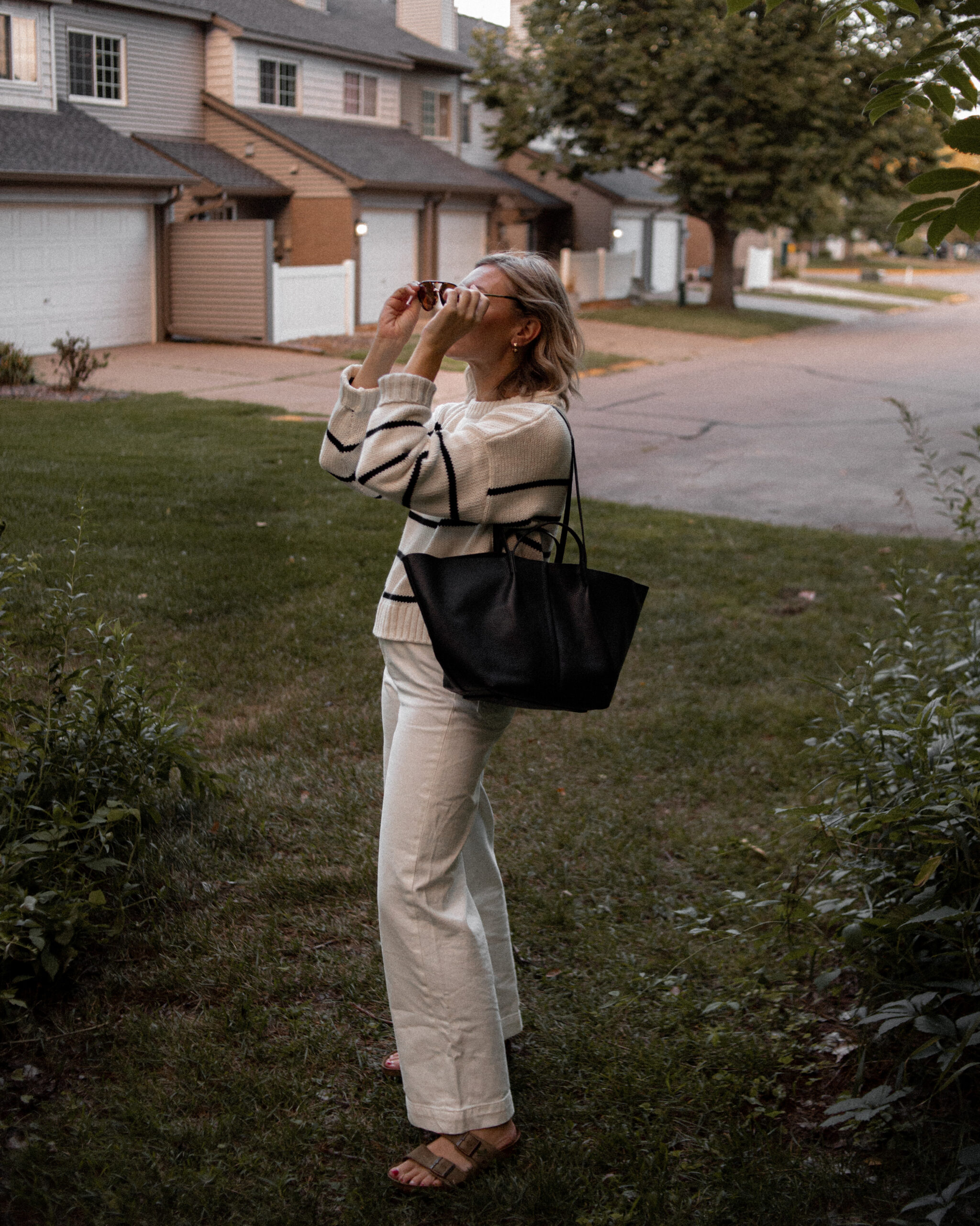 Karin Emily wears a jenni kayne striped sweater, white wide leg pants, birkenstock arizona sandals and a black bag from the Nordstrom Anniversary Sale
