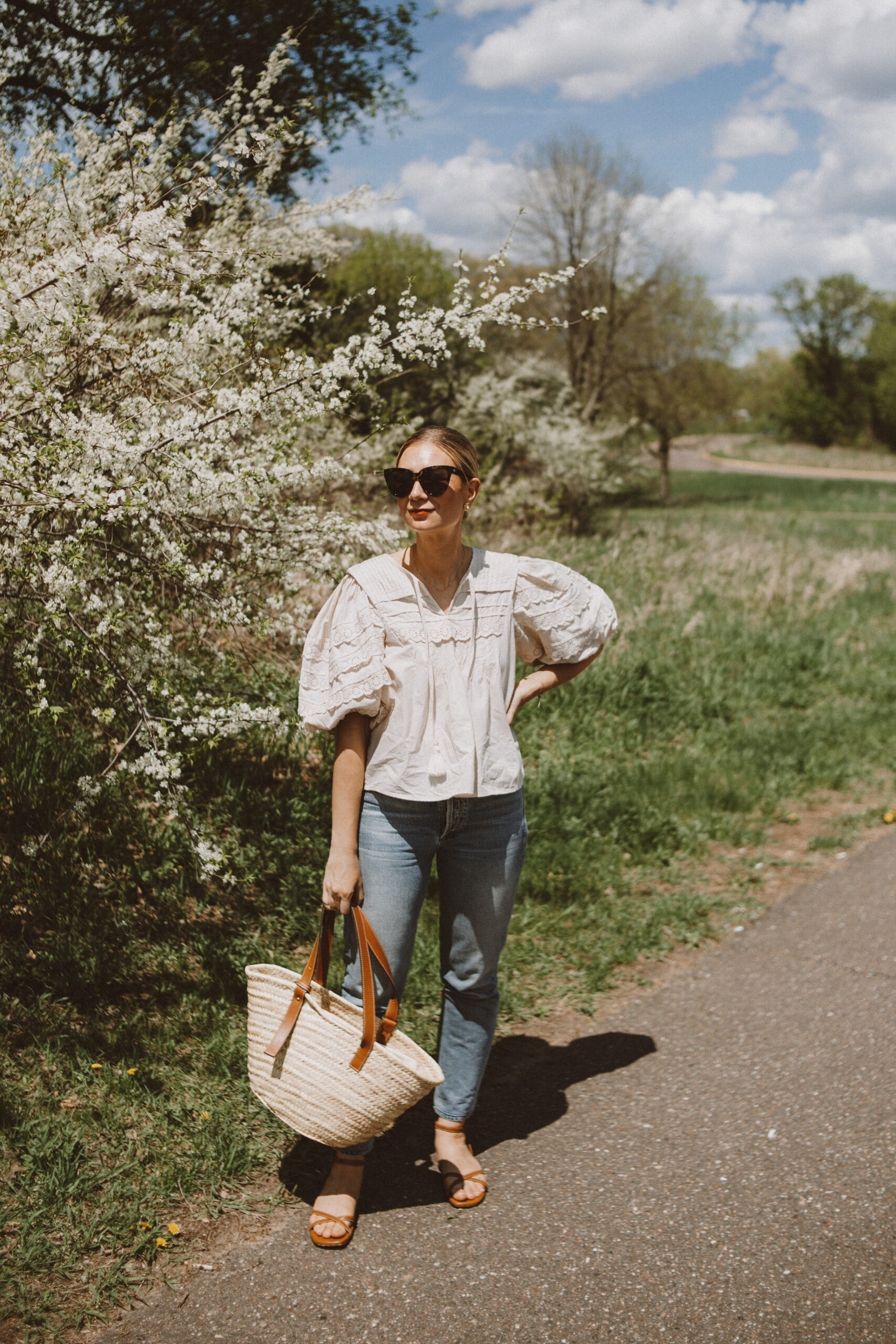 Karin Emily wears a lace puff sleeve top from SEA, Charlotte Jeans from Citizens of Humanity, and brown strappy sandals
