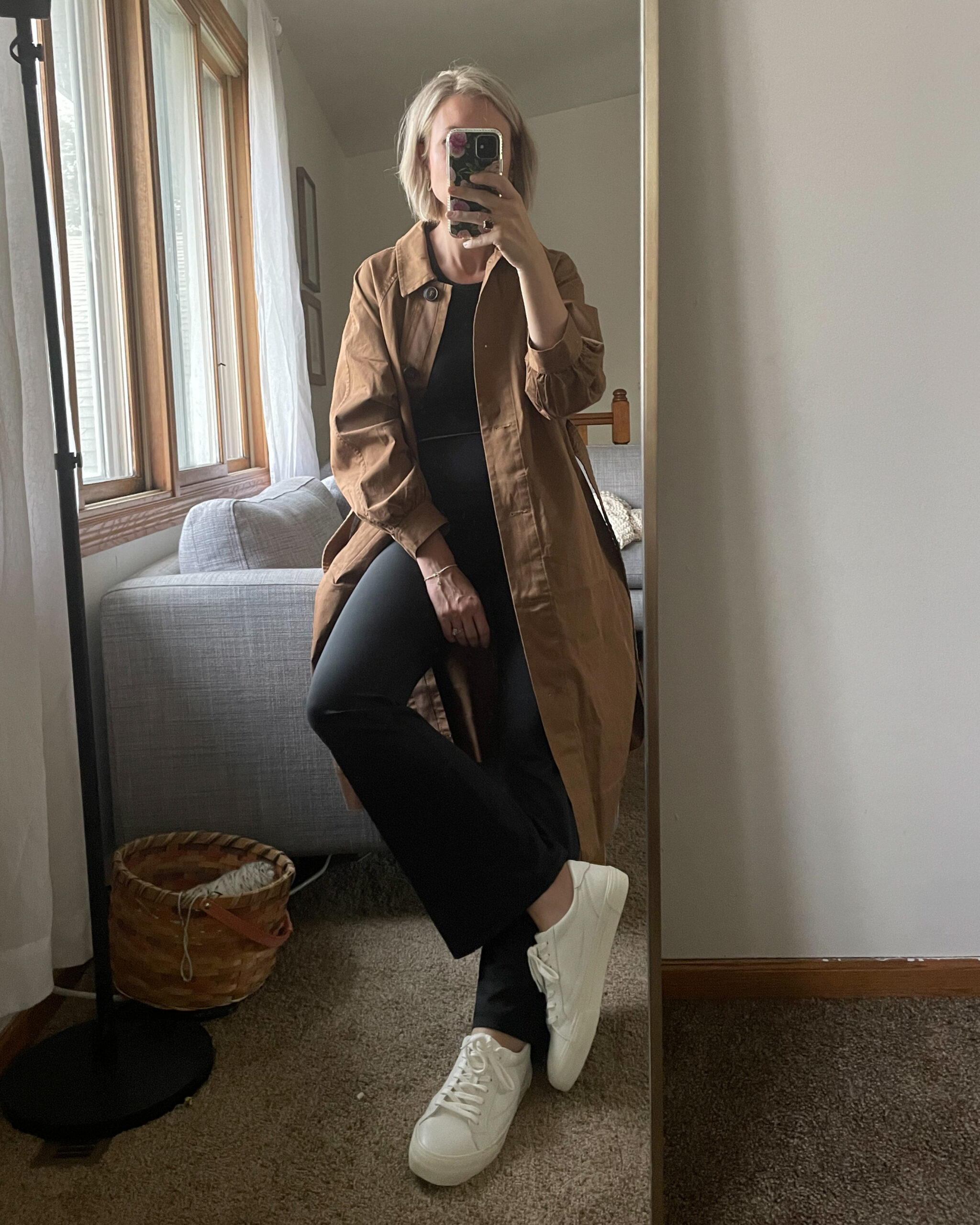 Karin Emily wears the perfect trench coat for fall from Madewell with a pair of black flare leggings and white sneakers