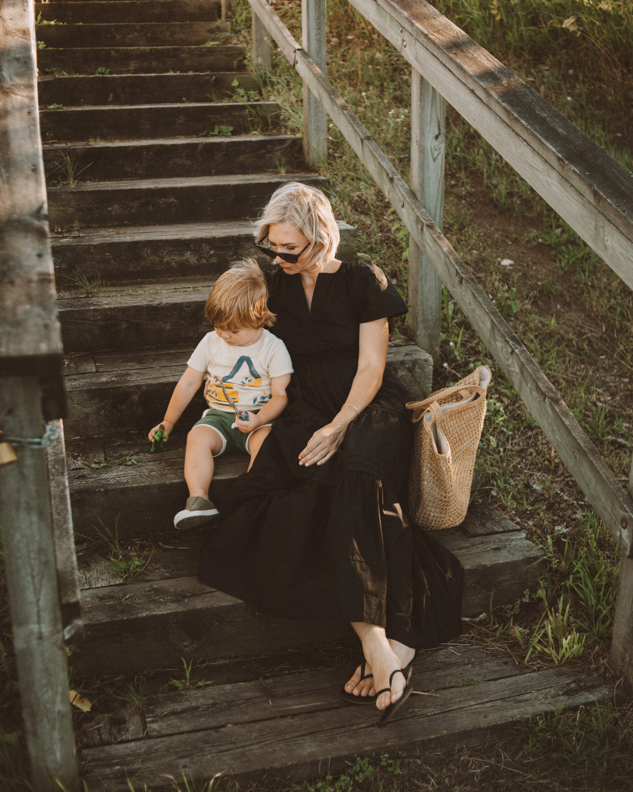 Karin Emily wears a black maxi dress with black sandals and a woven bag