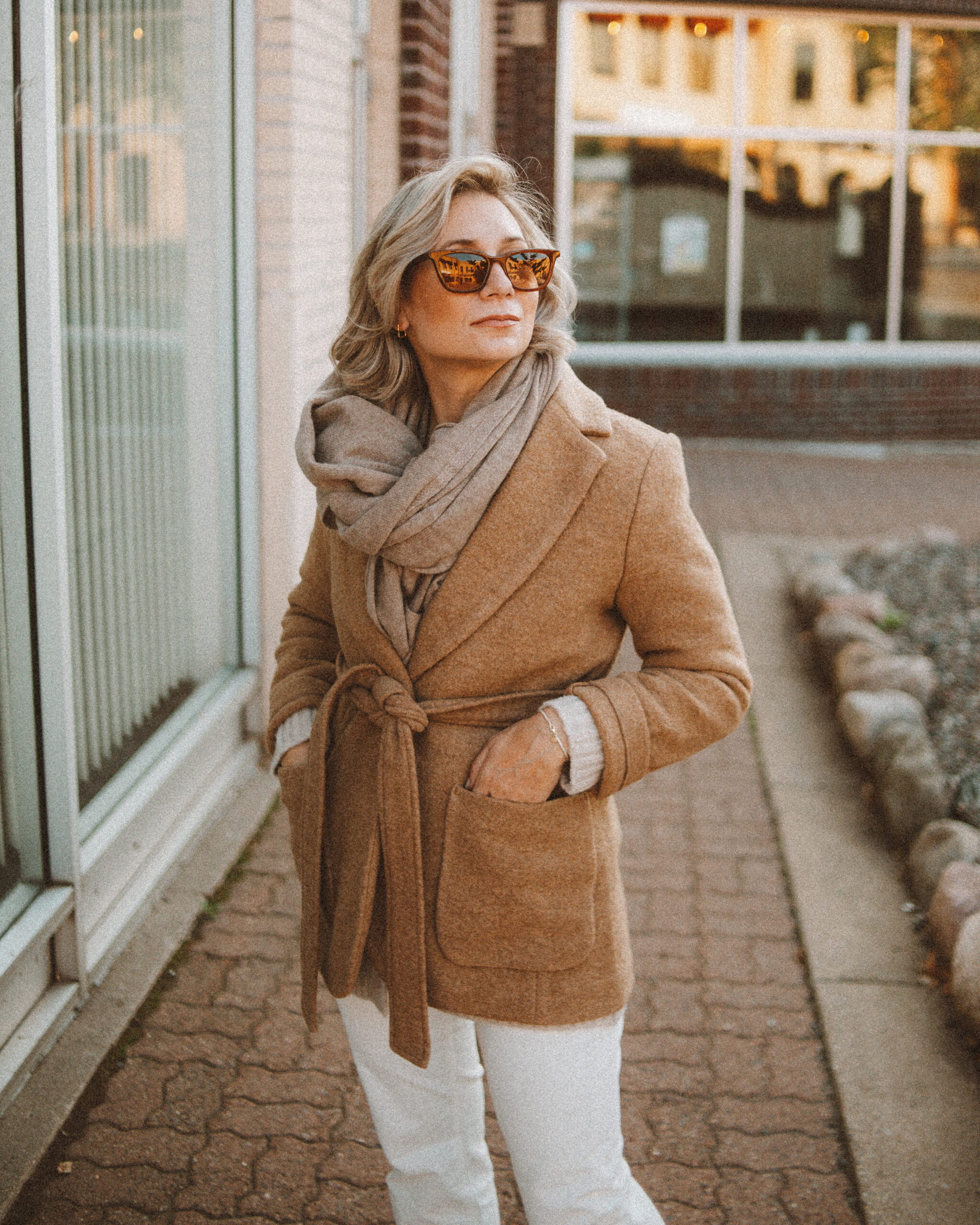 Karin Emily wears the perfect pair of corduroy pants with a cable knit cardigan, tan sneakers, cashmere scarf, and camel wool blazer coat