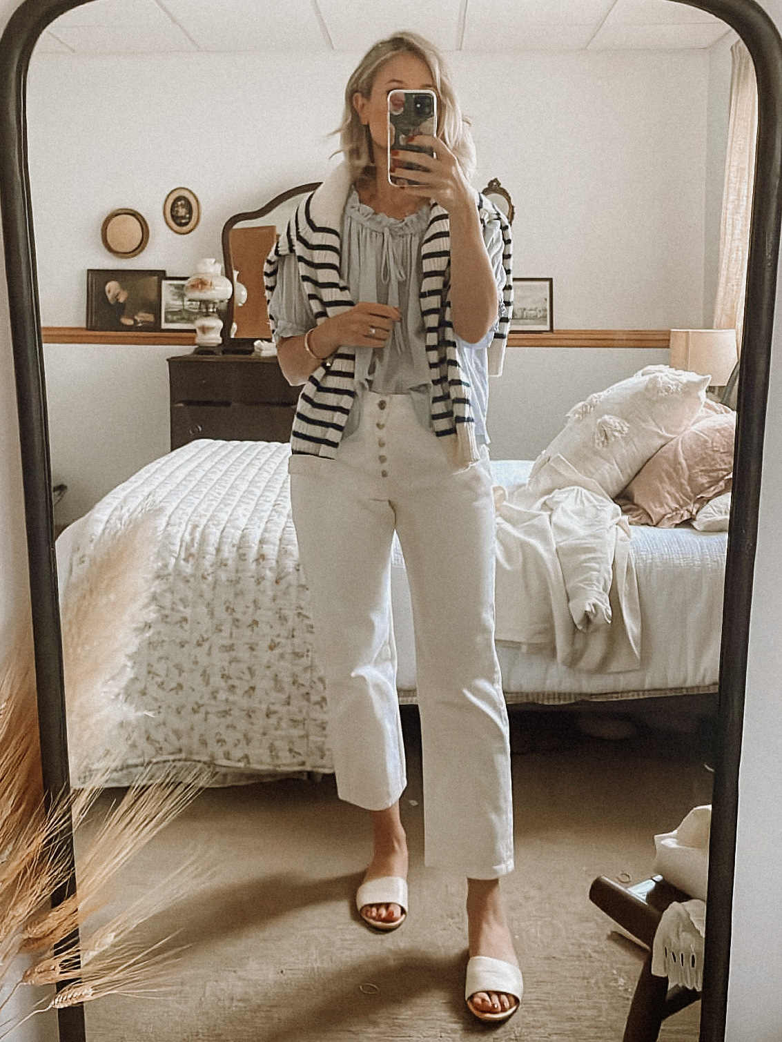 Karin Emily wears a low waisted white jeans, a blue doen blouse, and a striped cashmere sweater