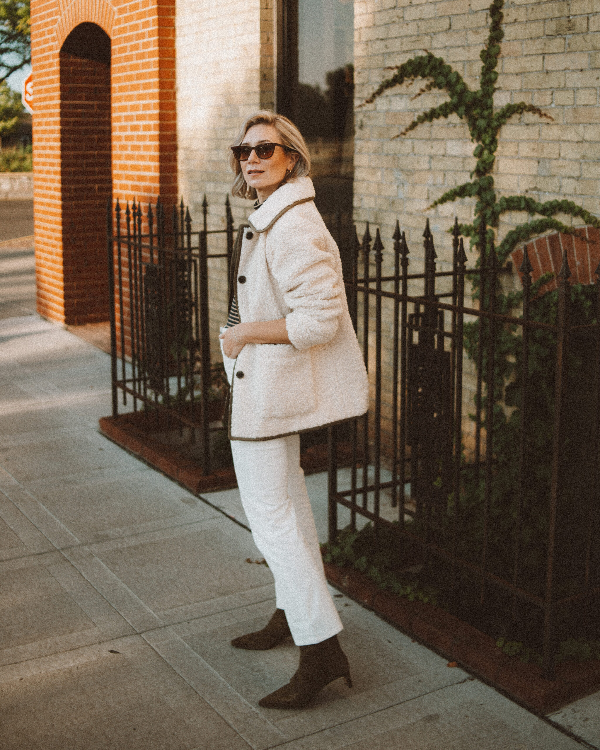 Karin Emily wears the perfect pair of corduroy pants with a cable knit cardigan, tan sneakers, cashmere scarf, and camel wool blazer coat