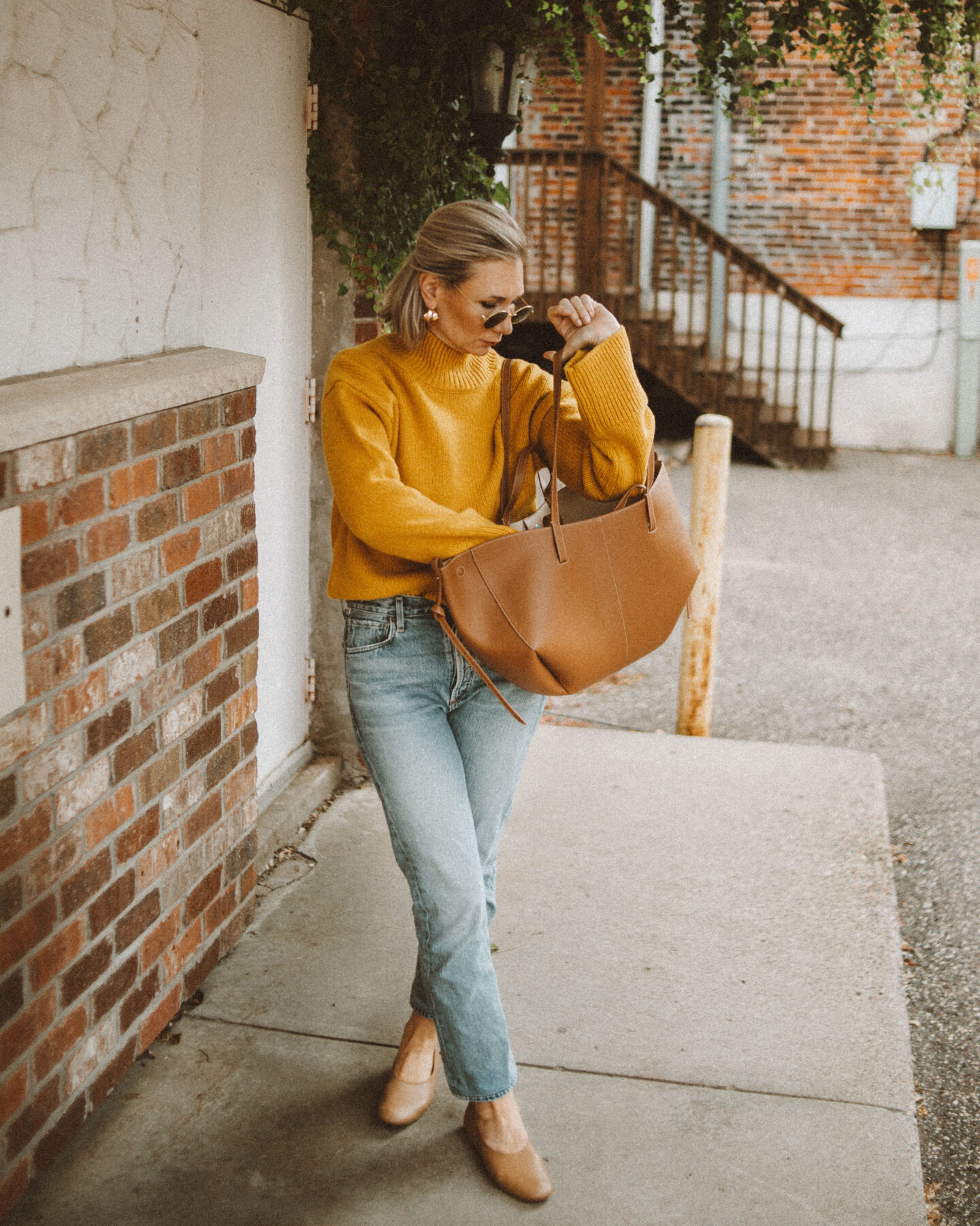 Karin Emily wears a goldenrod yellow turtleneck sweater from Alex Mill with her favorite Charlotte Jeans from CItizens of Humanity, a Polene Cyme Bag, Everlane Day Glove Flats, and chunky gold jewelry