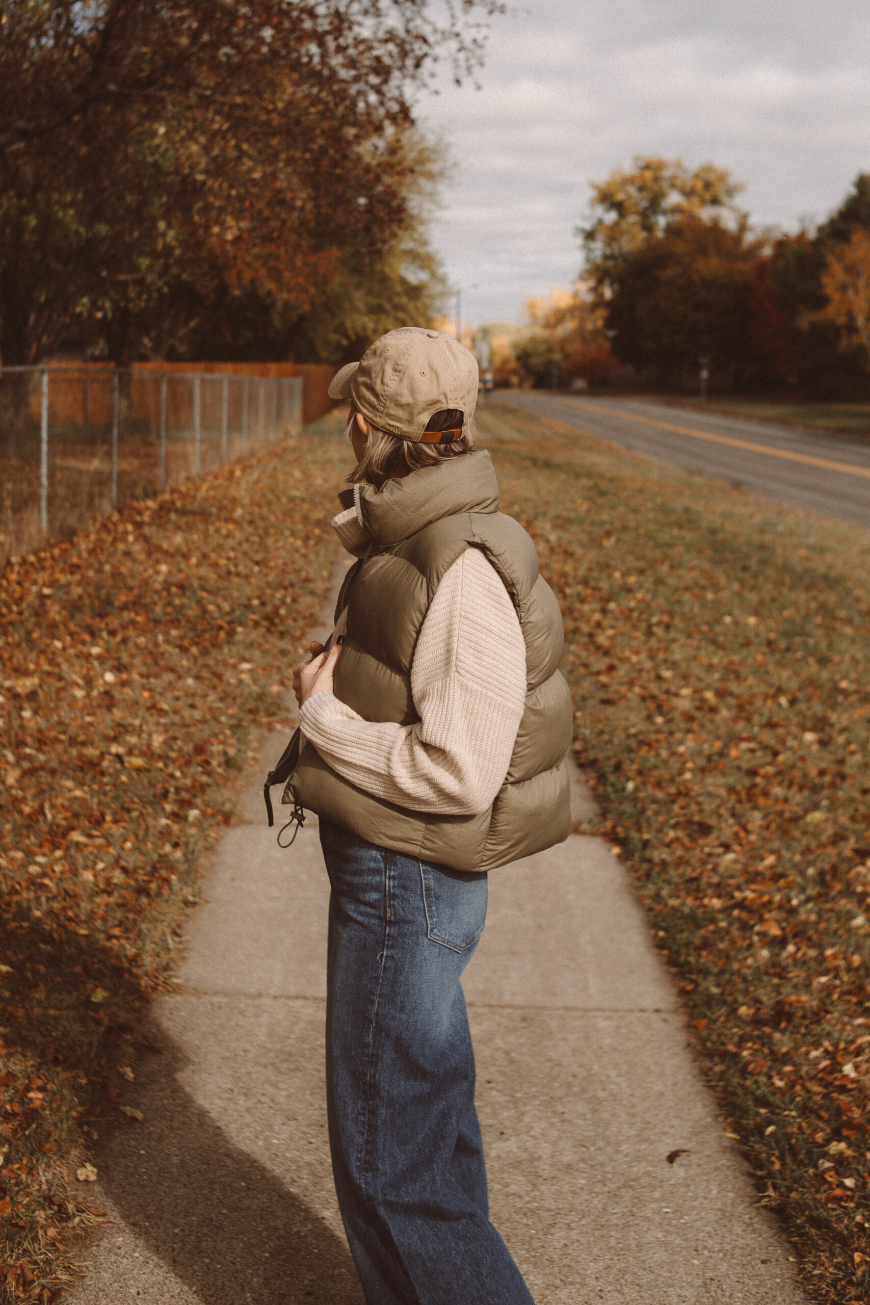 Karin Emily wears a fall mom outfit with a cropped cashmere turtleneck sweater, cropped puffer vest, wide leg jeans, and suede cowboy boots