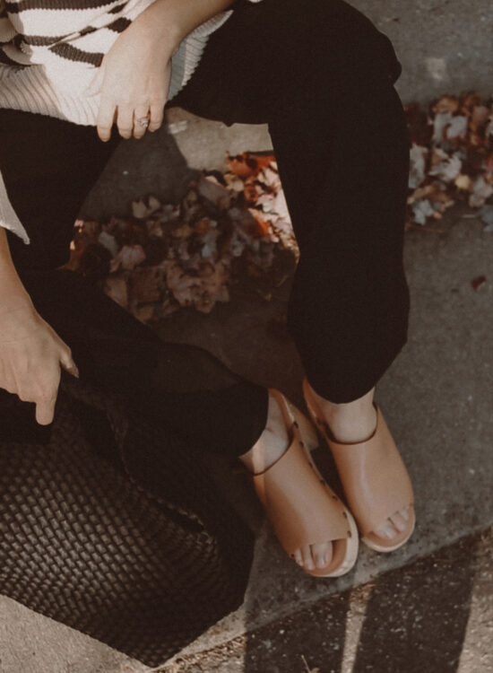 Karin Emily wears a pair of wooden blogs and black wide leg pants