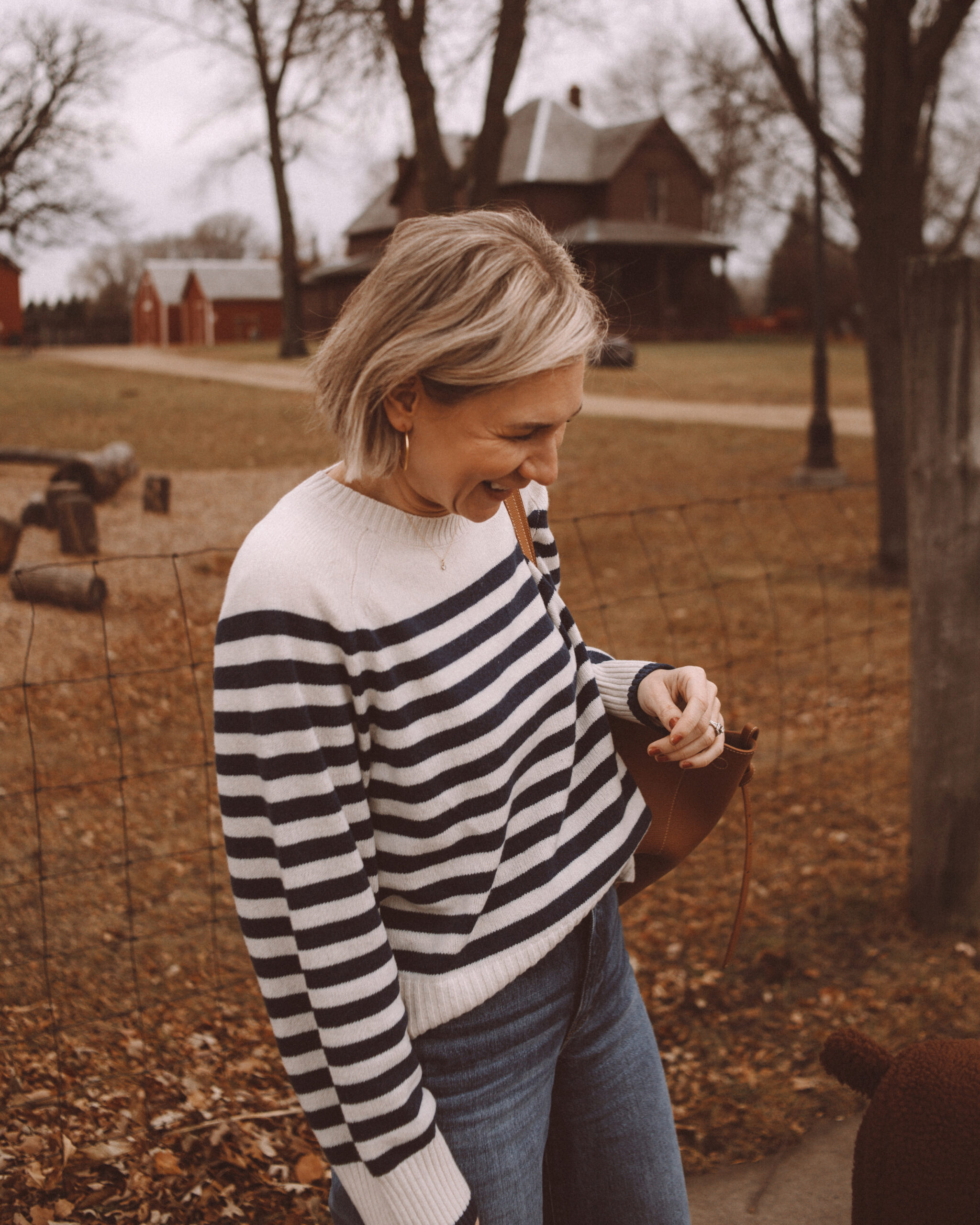 Karin Emily wears a striped cashmere sweater and dark wash jeans with a polene tote bag