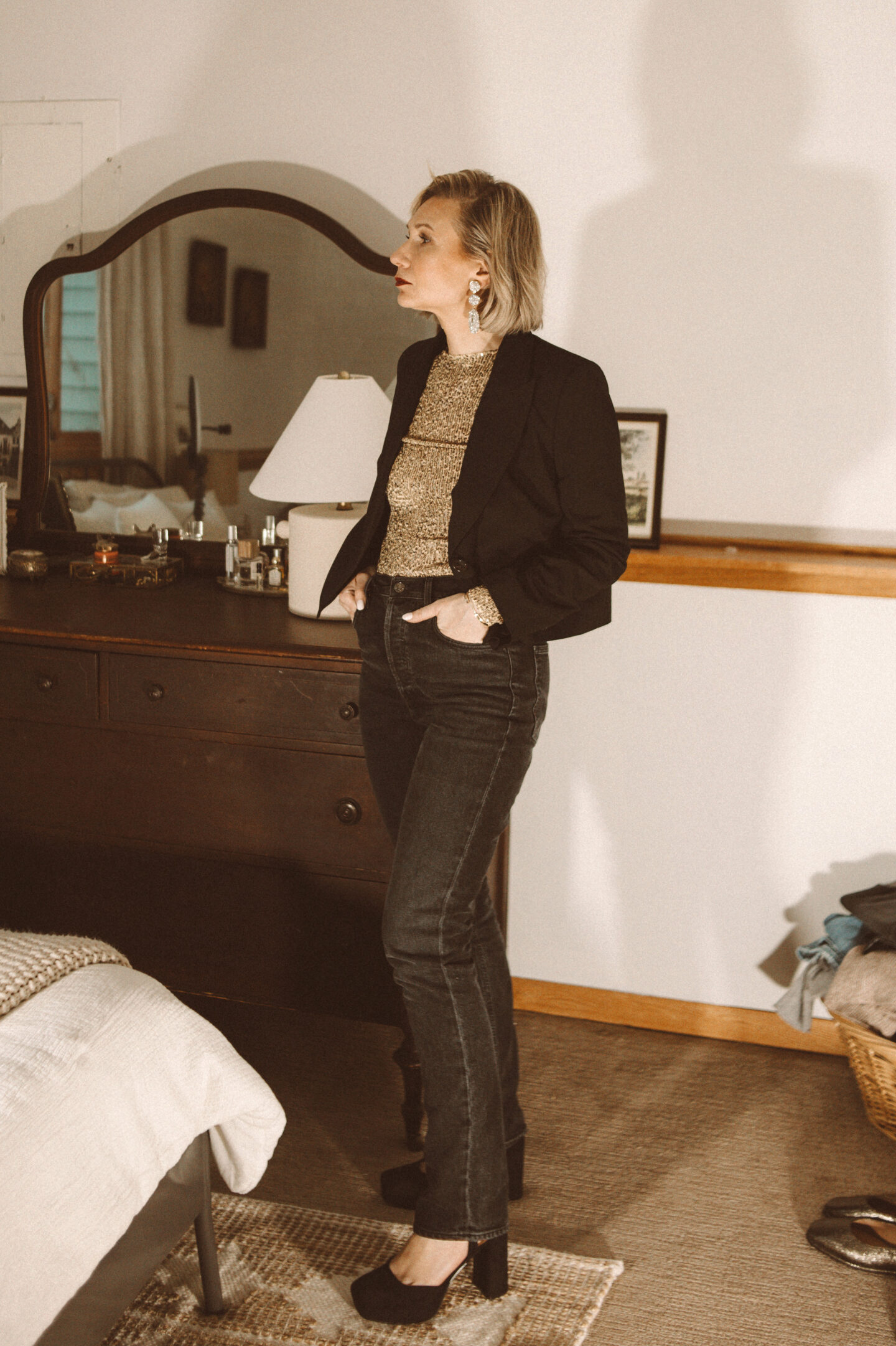 Karin Emily wears a cropped blazer with a sequin top, black agolde jeans, and black platform heels