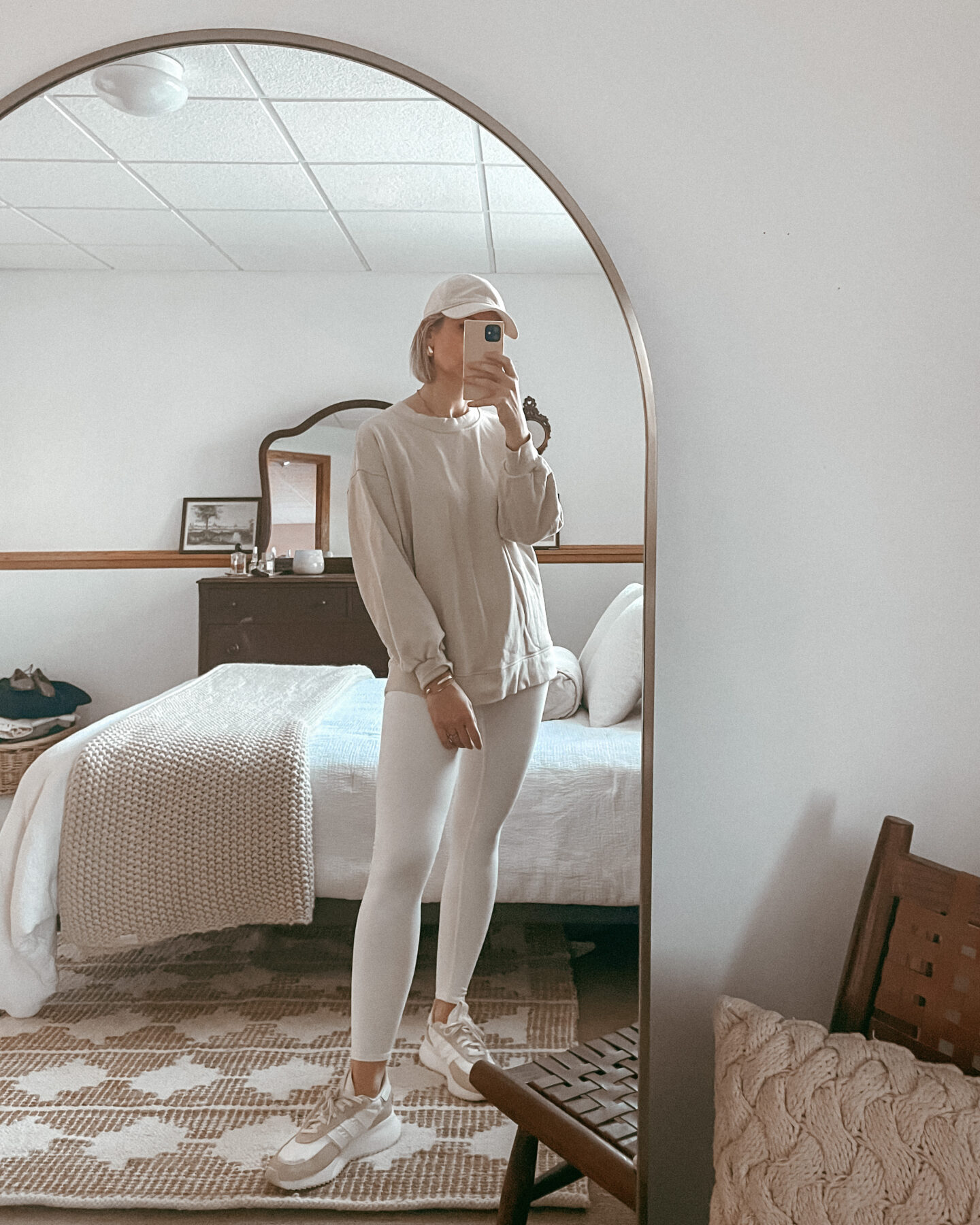 Karin Emily wears a leggings outfit with alo yoga white leggings, a light tan sweatshirt from lululemon, and neutral colored adidas sneakers