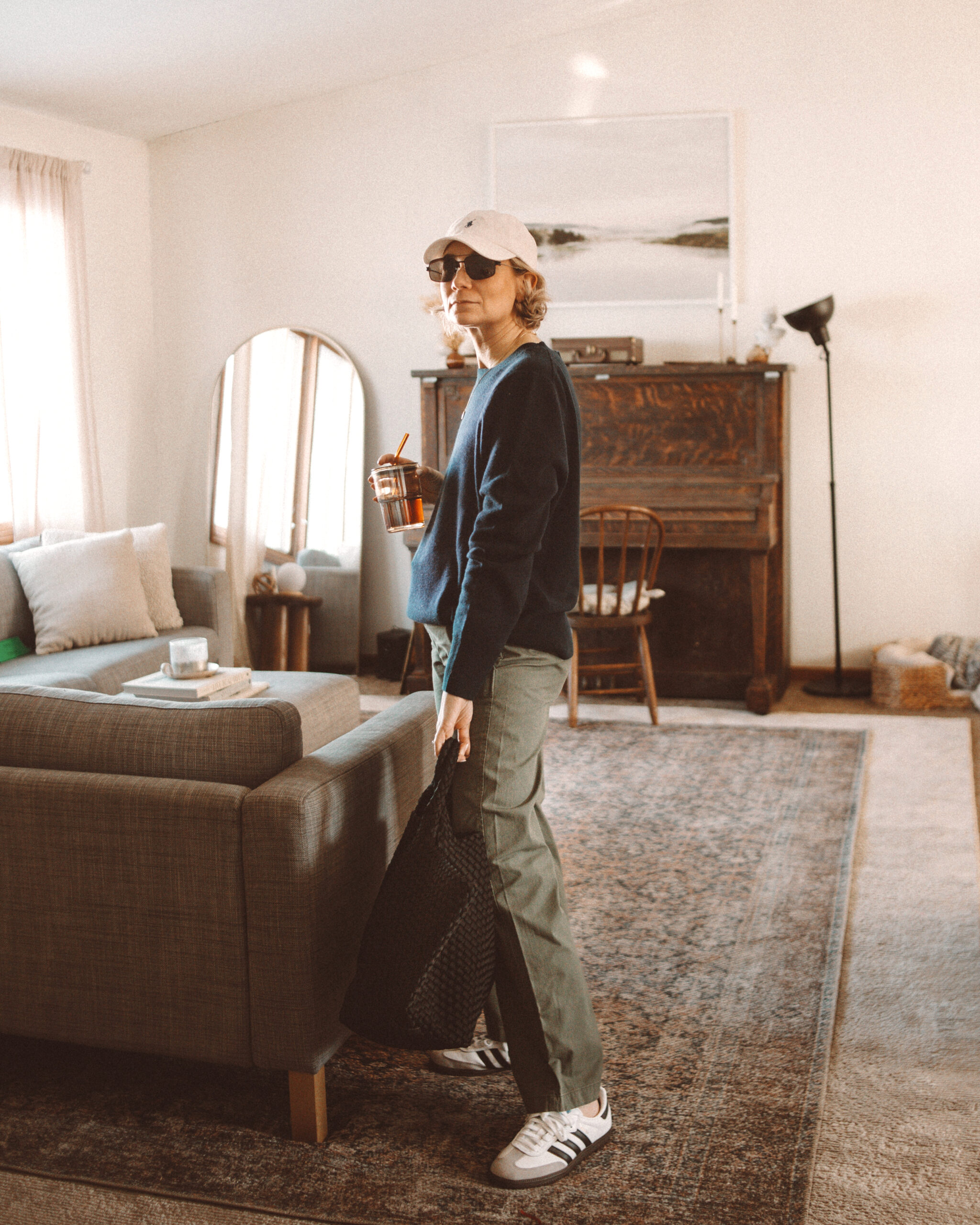 Karin Emily wears a navy blue cashmere sweater and green khaki sailor trousers from J. Crew with a pair of adidas samba sneakers and a naghedi st. Barths bag