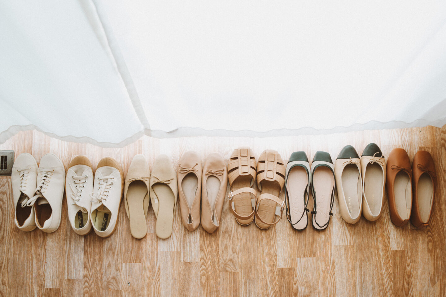Karin Emily fhares a line up of her favorite spring shoes on the wood floor in front of her white curtains