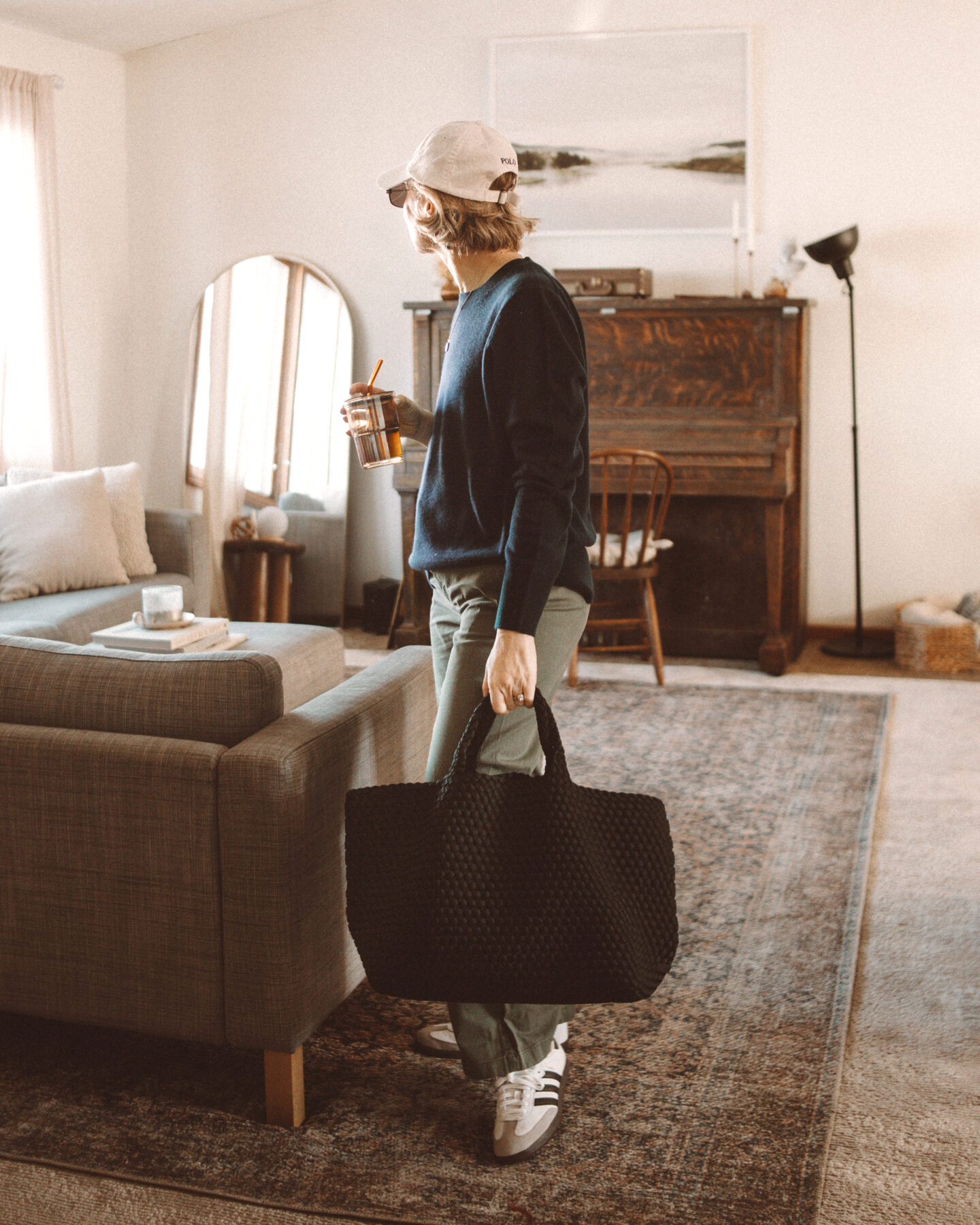 Karin Emily wears a navy blue cashmere sweater and green khaki sailor trousers from J. Crew with a pair of adidas samba sneakers and a naghedi st. Barths bag