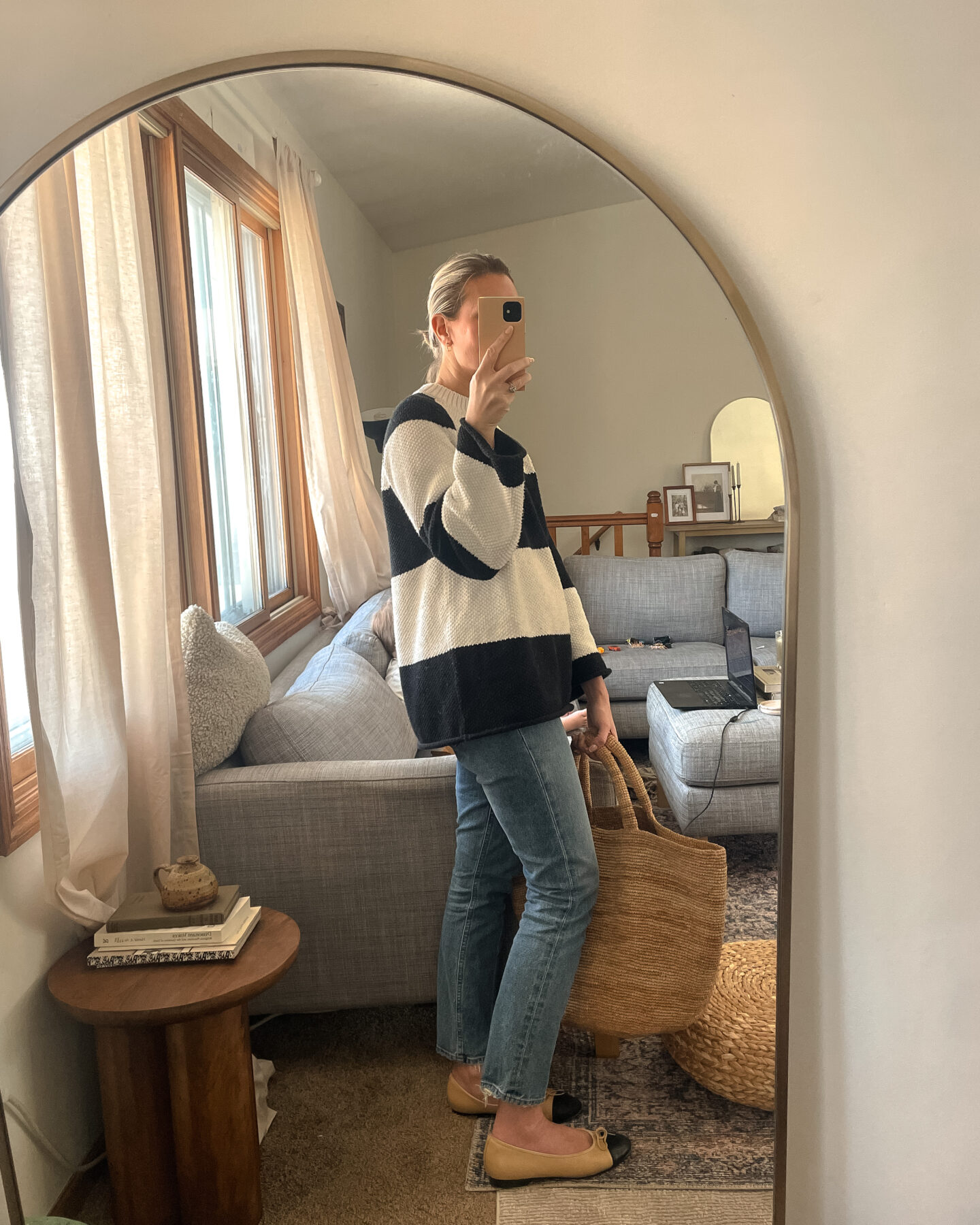 Karin Emily shares a mirror selfie wearing a striped sweater, straight leg jeans and a basket bag
