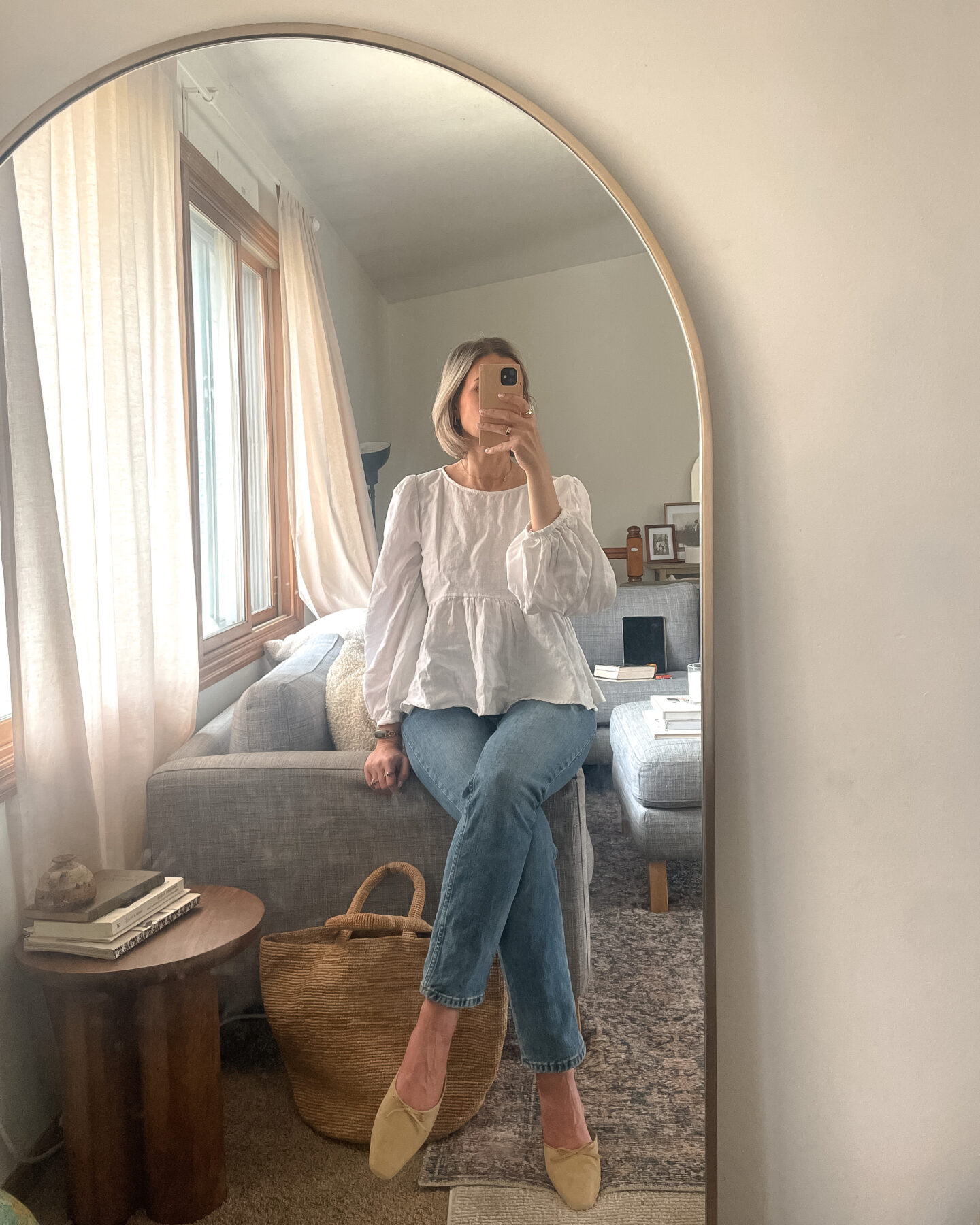 Karin Emily shares a mirror selfie wearing a linen peplum top, straight leg jeans, and suede mules 