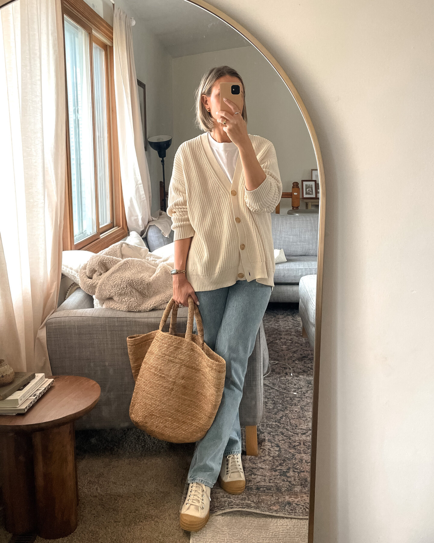 Karin Emily shares a mirror selfie in a jenni kayne cotton cardigan, agolde lana jeans, canvas sneakers and straw bag