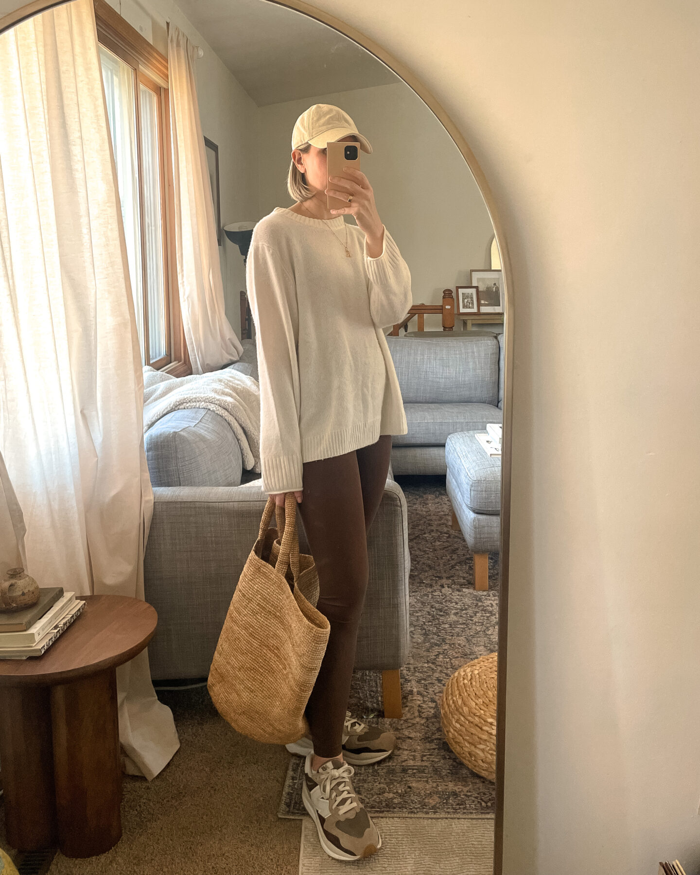 Karin Emily shares a mirror selfie wearing an oversized cashmere sweater, brown lululemon leggings, brown new balance sneakers and a straw tote