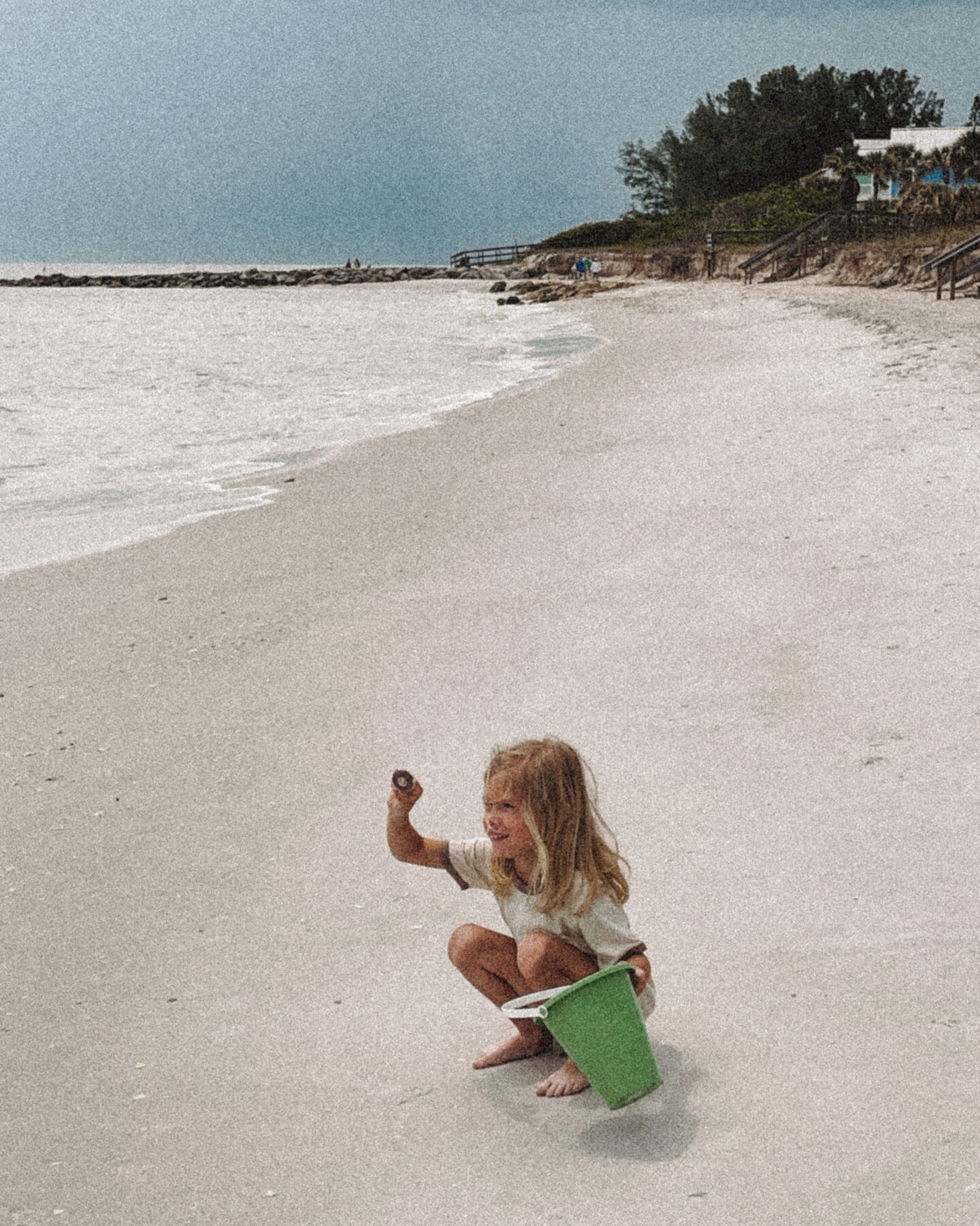 A little girl looks for shells in the sand on the beach