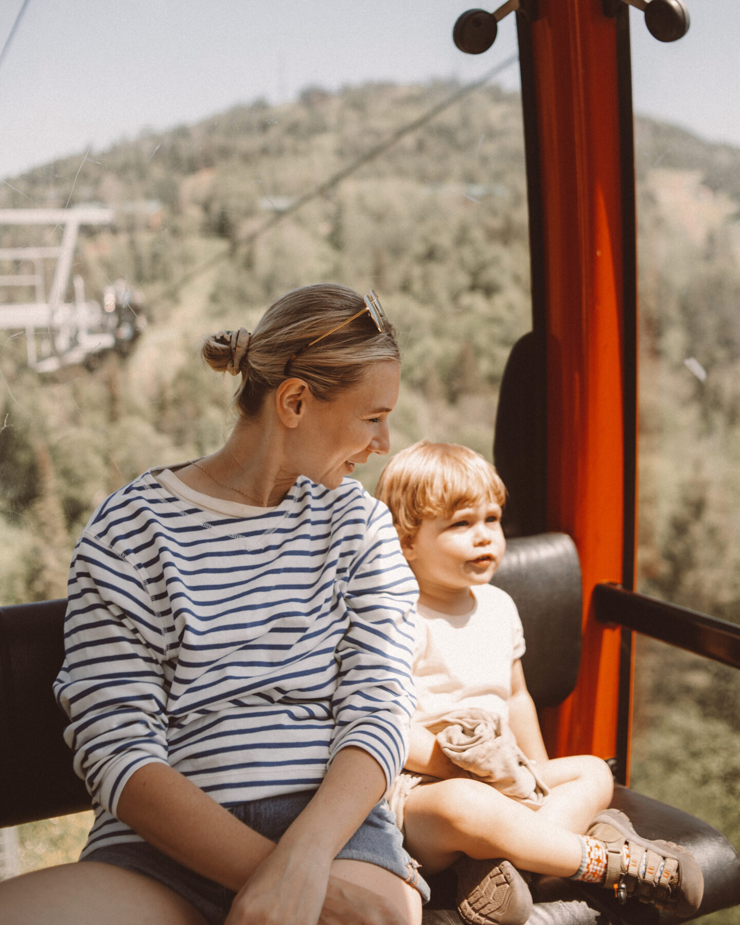 Karin Emily and her son sit on a gondola and she wears a striped blue and white long sleeve tee