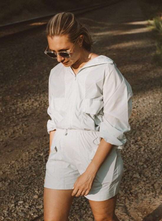 Karin Emily wears a hiking set from NEIWAI while standing in front of an outdoor wooded area