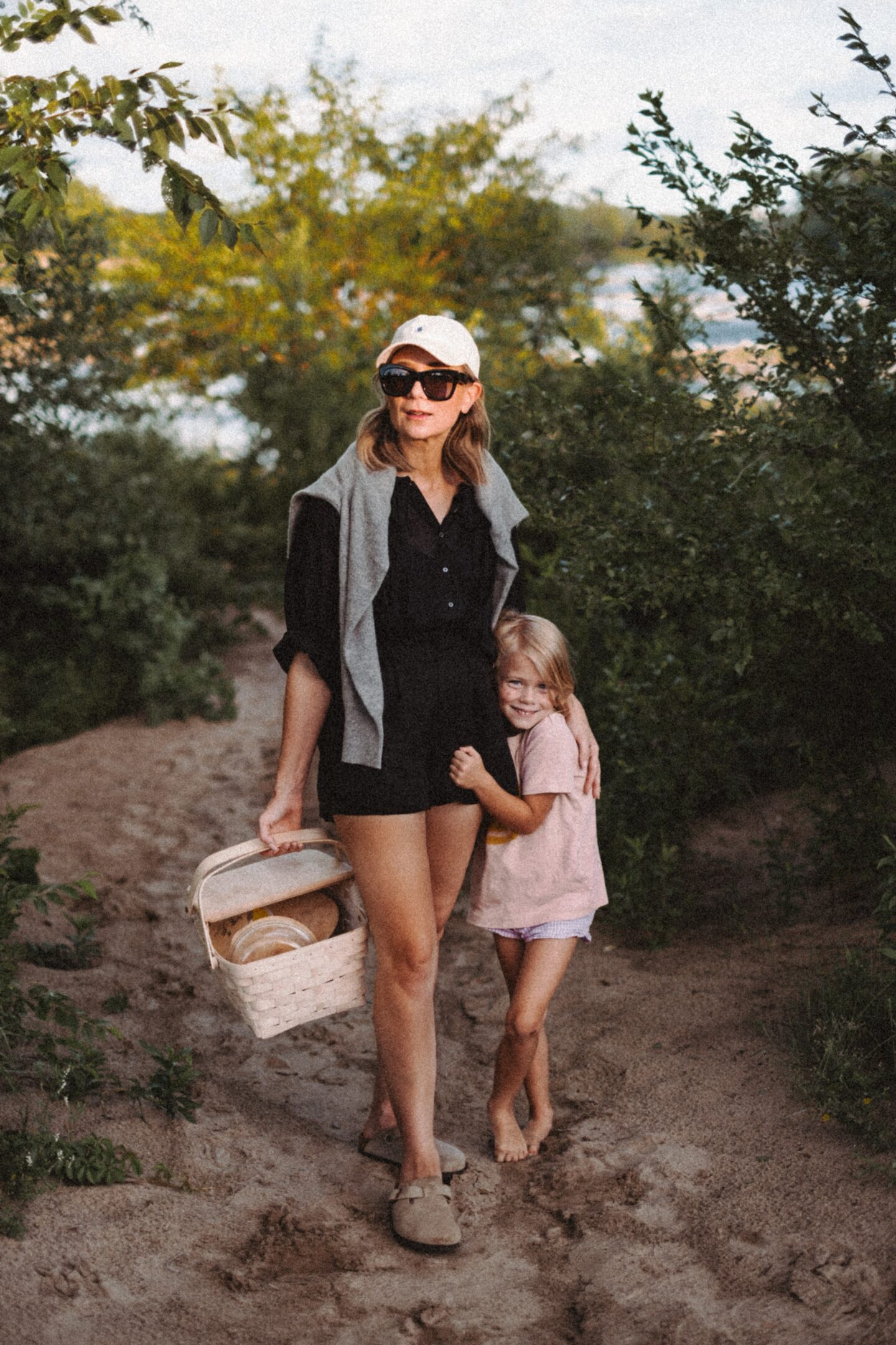 Karin Emily stands with her daughter in front of a beach path and wears the Jana top from the pre fall at Doen collection 