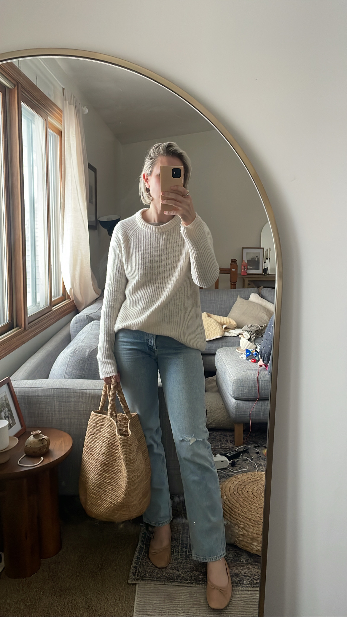 Karin Emily wears a cream, ribbed cashmere sweater with a pair of ripped knee straight leg jeans, and nude flats with a basket bag and the sweater is on sale for Black Friday Sales