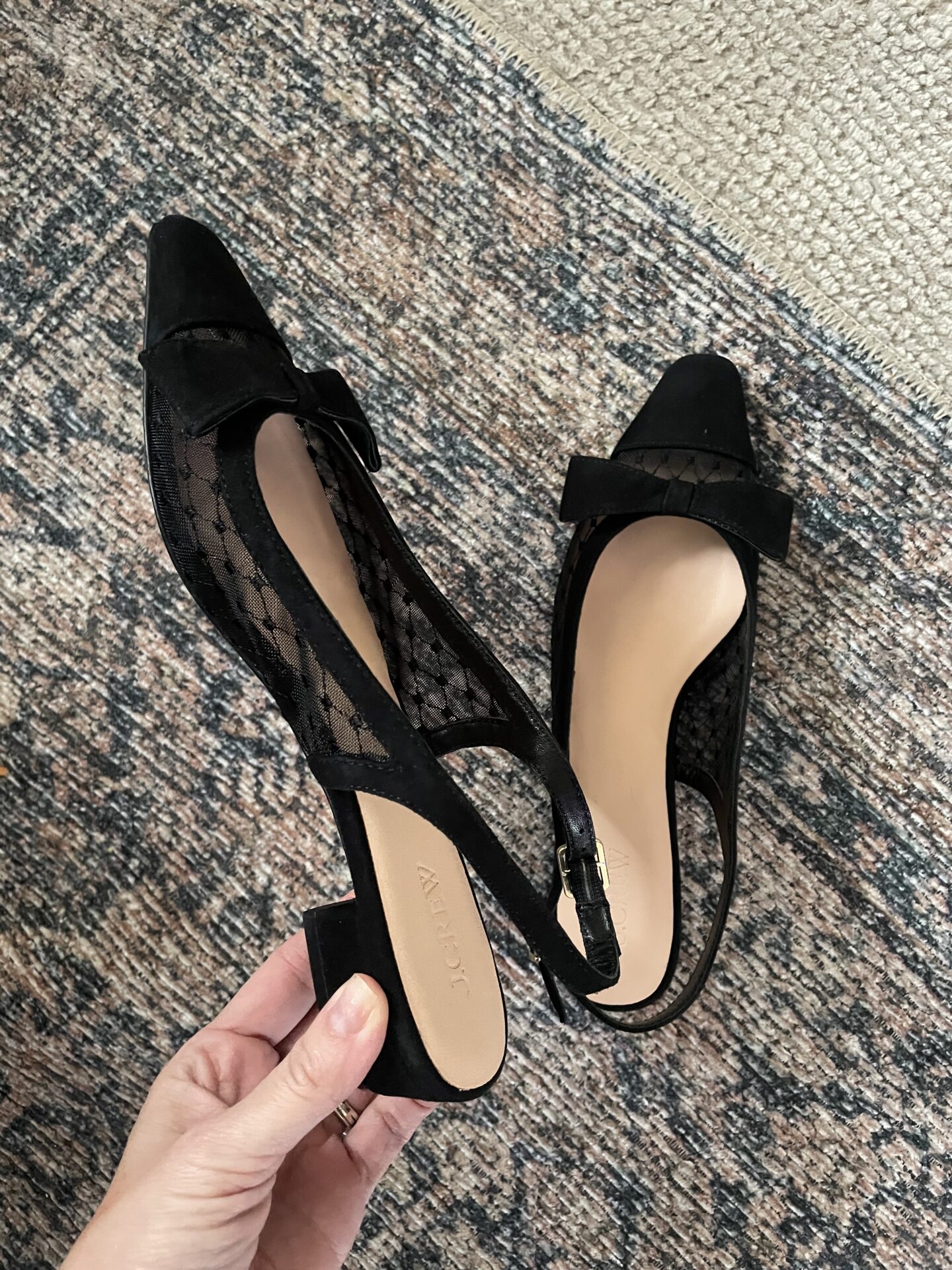 Karin Emily shares a close up of a pair of party shoes that have black sheer details on the side with a black velvet bow and a black cap toe.