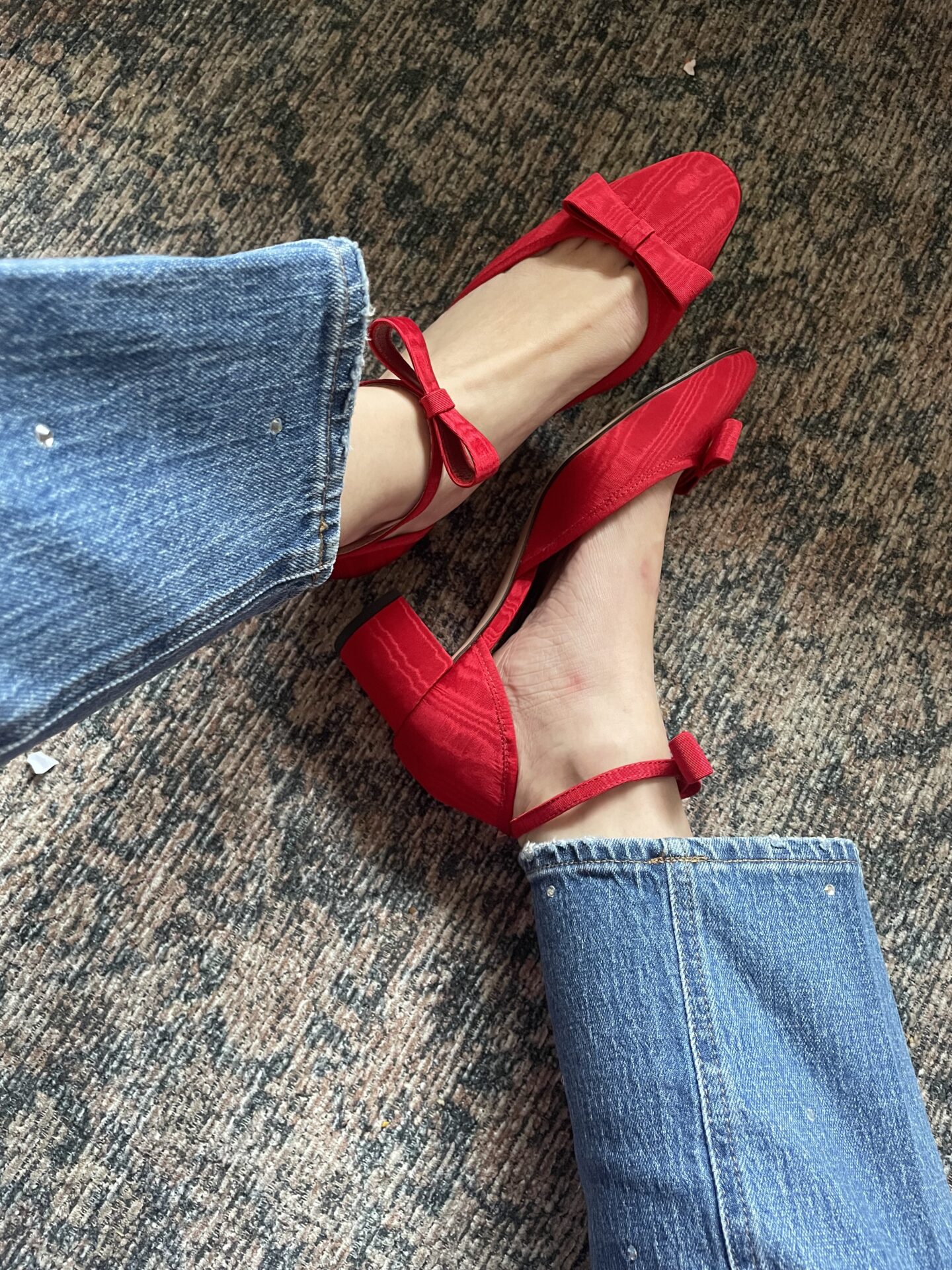 Karin Emily sits on the floor and shows a close up of her jeans that have jewels encrusted all over them and she paired them with a pair of red, bow heels . Both are on sale for the Black Friday sales