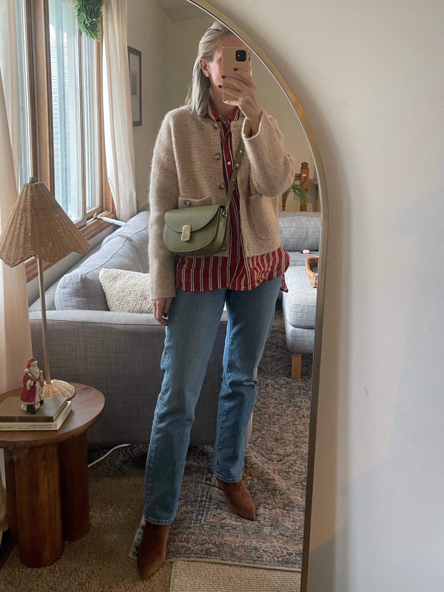 Karin Emily wears a tan wool bomber coat over a burgundy button down with straight leg jeans with brown boots