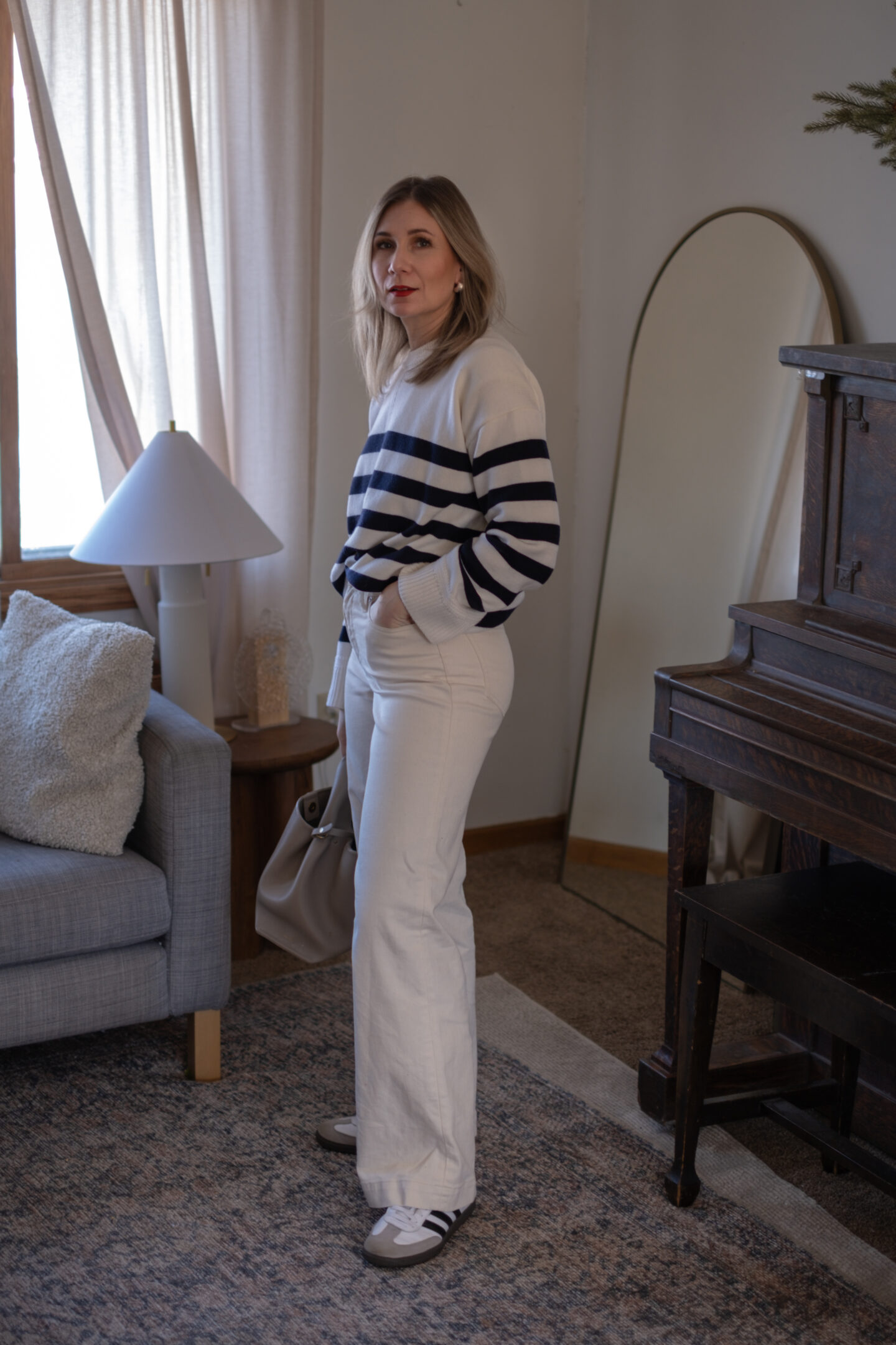 Karin Emily wears her white jeans for spring with a Breton stripe sweater and adidas samba sneakers