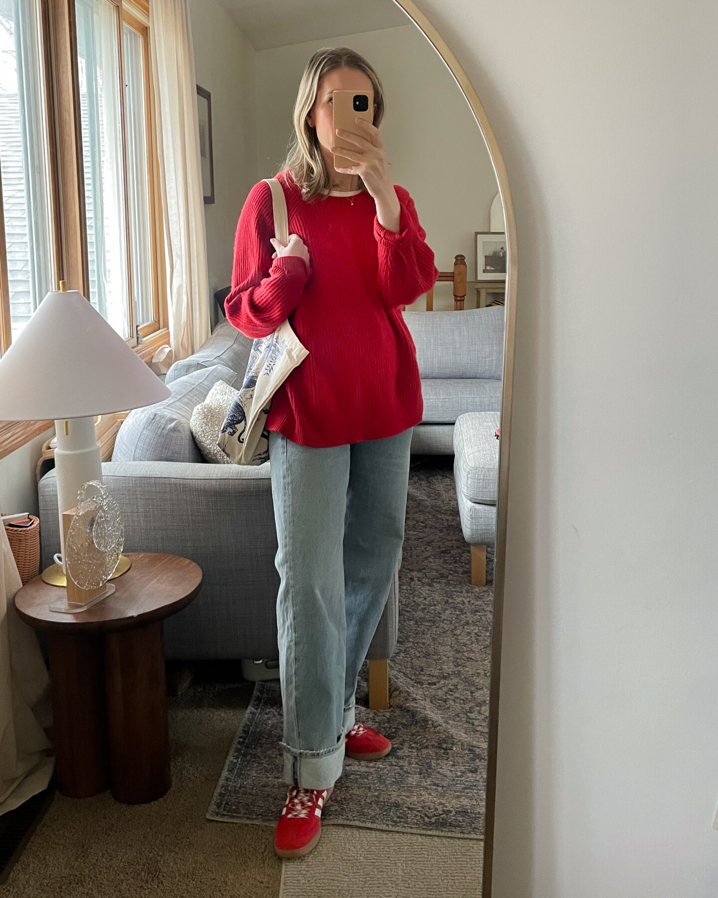 Karin Emily personal style wears an oversize red cashmere sweater over a pair of cuffed baggy light wash jeans with a pair of red Adidas Samba sneakers for a recent post about recent outfits