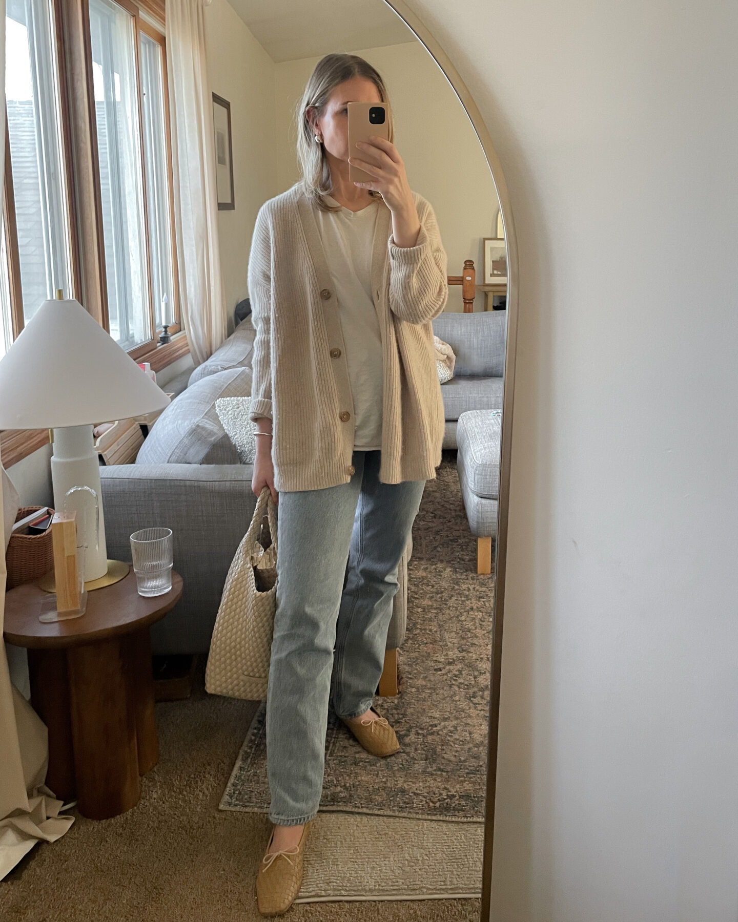 Karin Emily wears a Jenny Kane cashmere cocoon cardigan over an oversized white T-shirt with a pair of light wash Lana jeans from agolde and a pair of tan woven Jada Flats from Freda Salvador