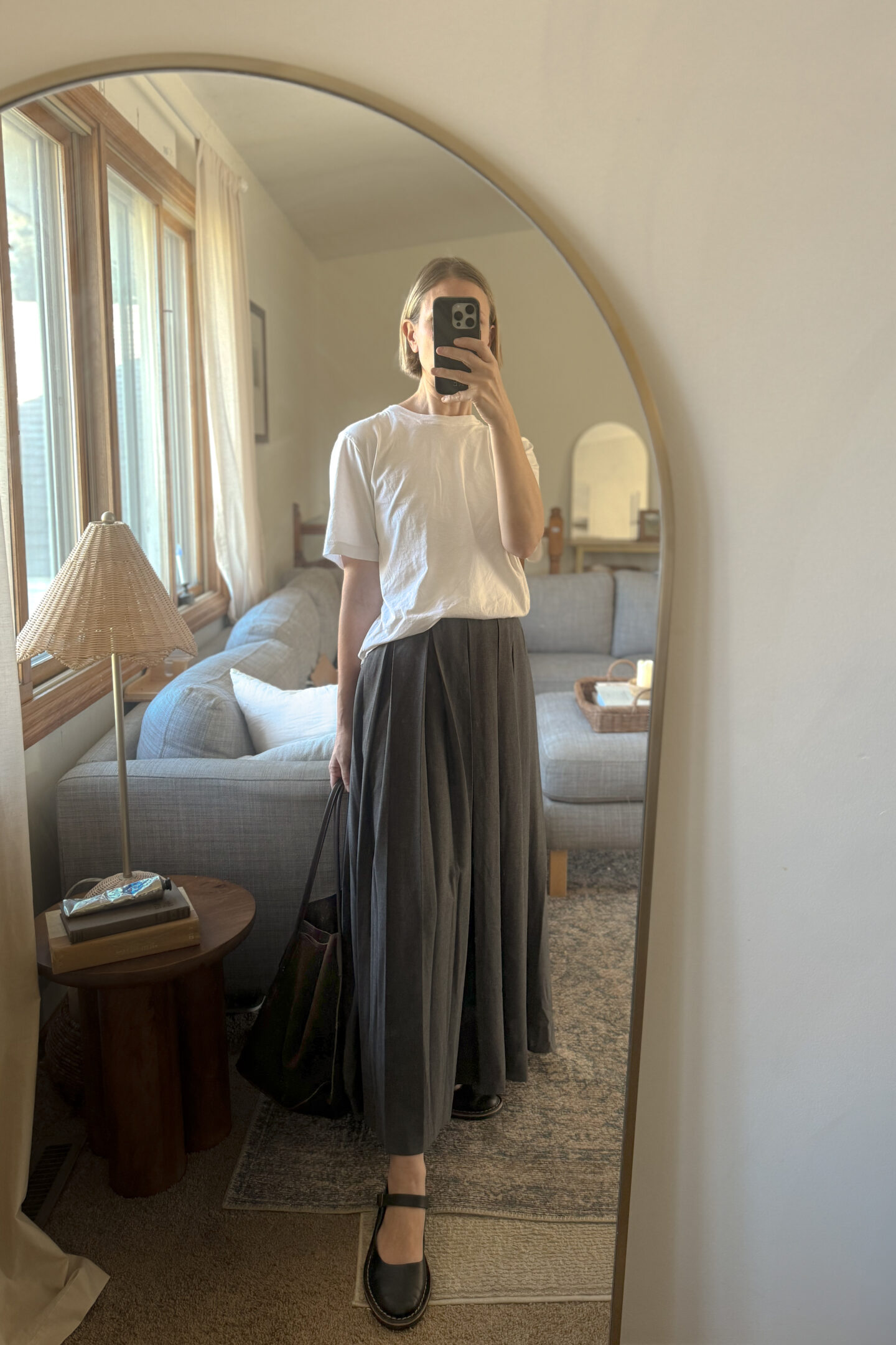 Karin Emily is selling all of her clothes but is still left with a gray maxi pleated skirt, a pair of black chunky Mary Jane flats, and a chocolate brown suede tote bag