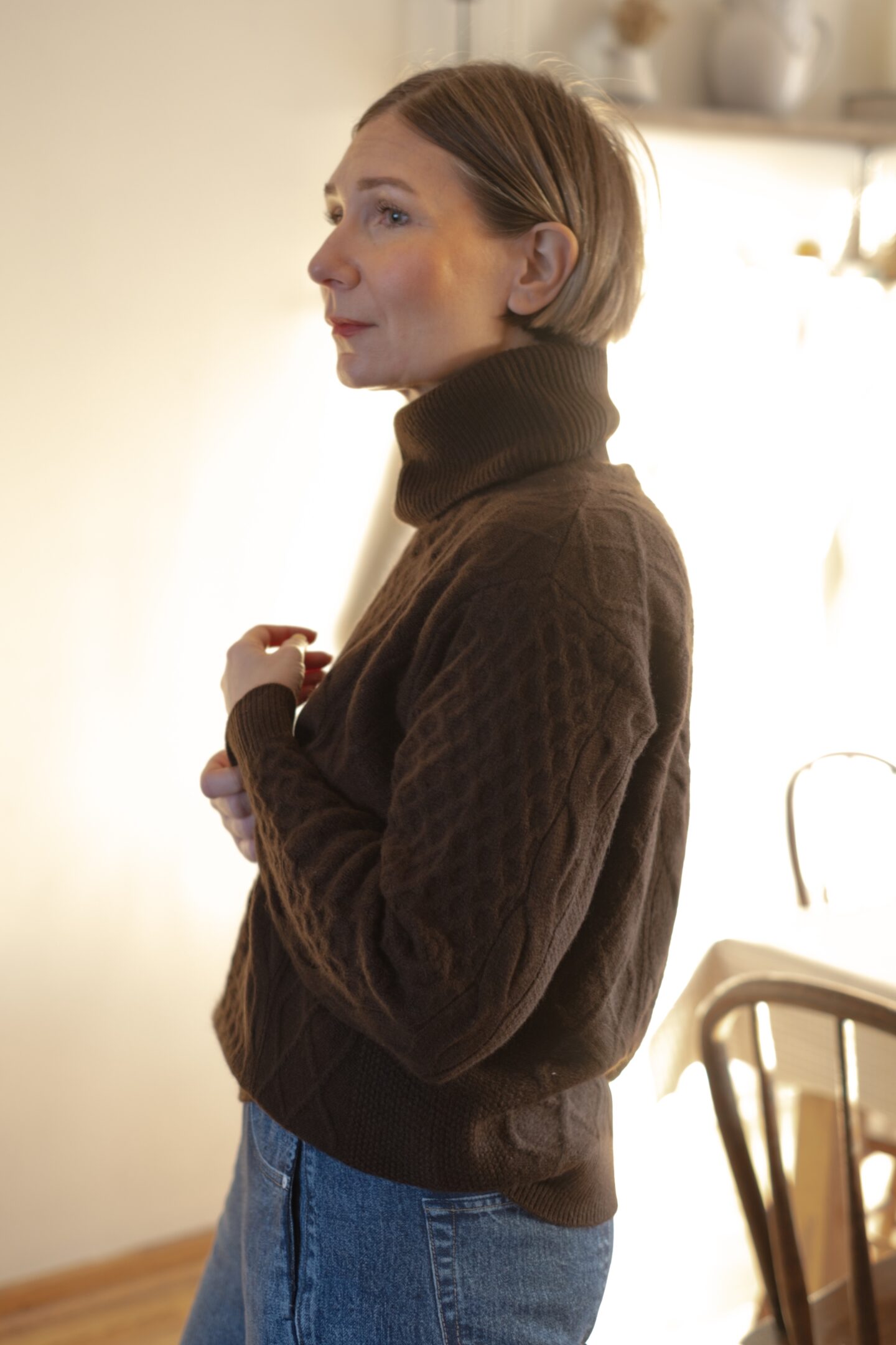 Karin Emily stands in her holiday decorated dining room and wears a chocolate brown monochrome outfit 