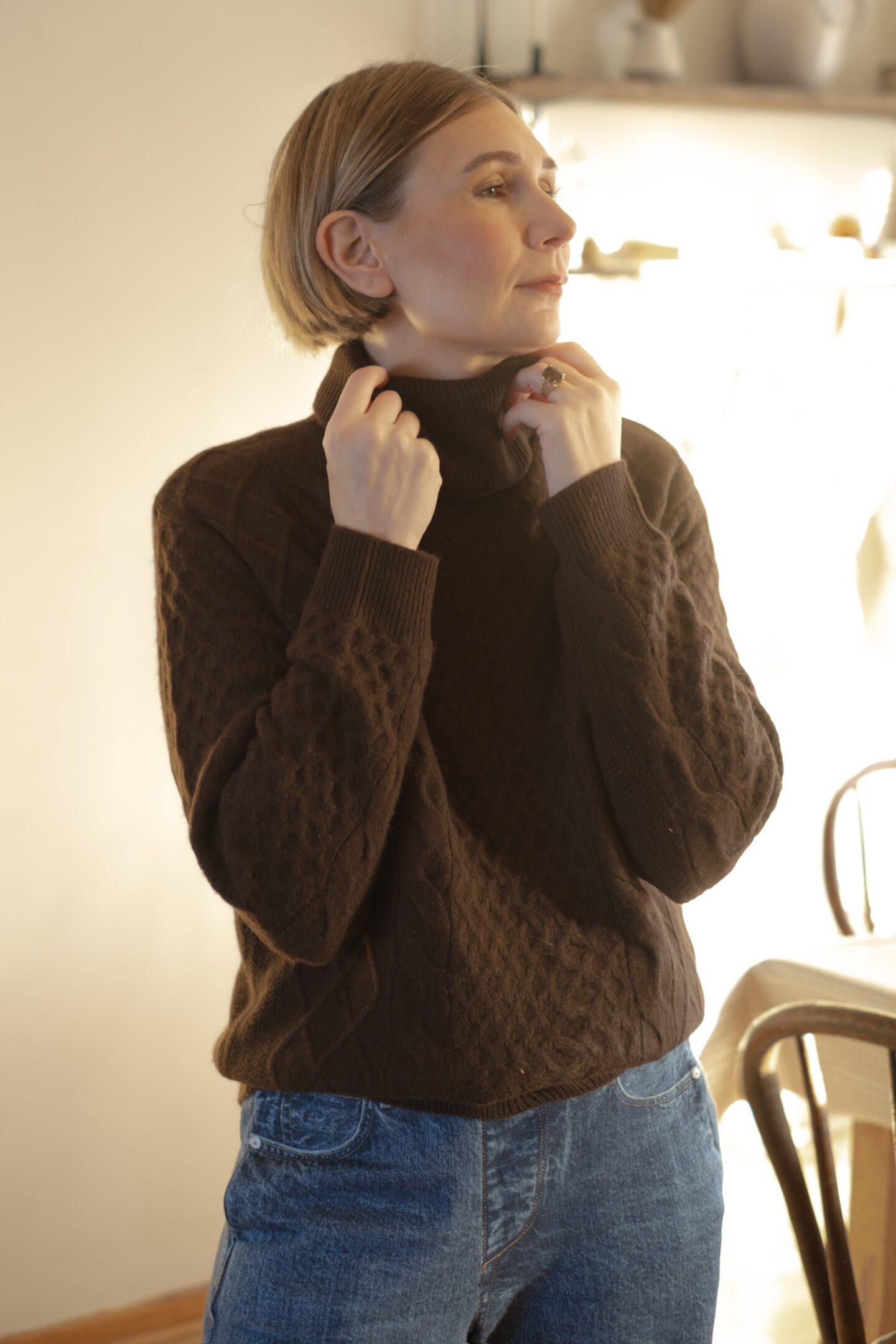 Karin Emily stands in her holiday decorated dining room and wears a chocolate brown monochrome outfit 