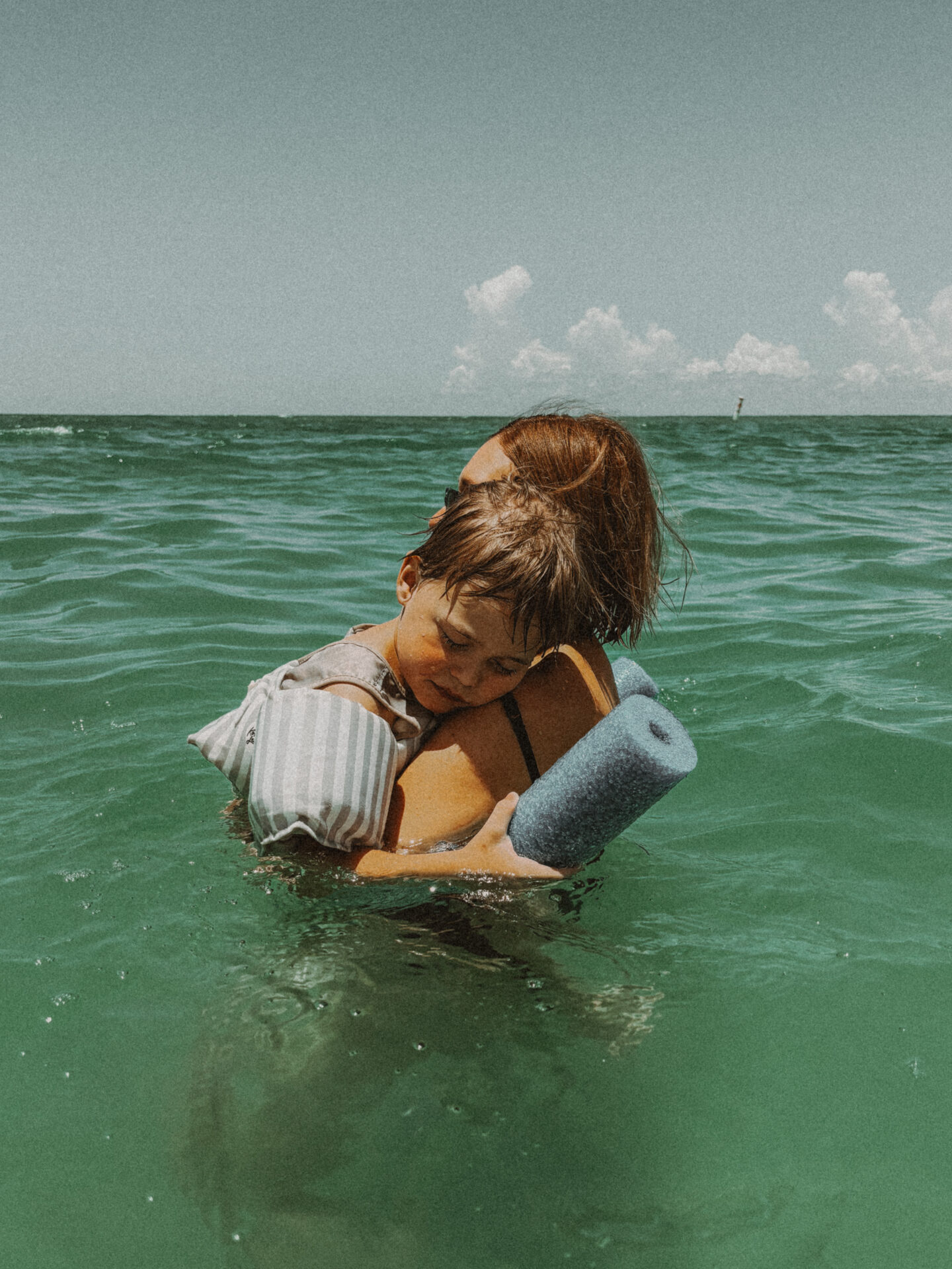 Karin Emily cuddles her sleeping son while floating in the ocean.