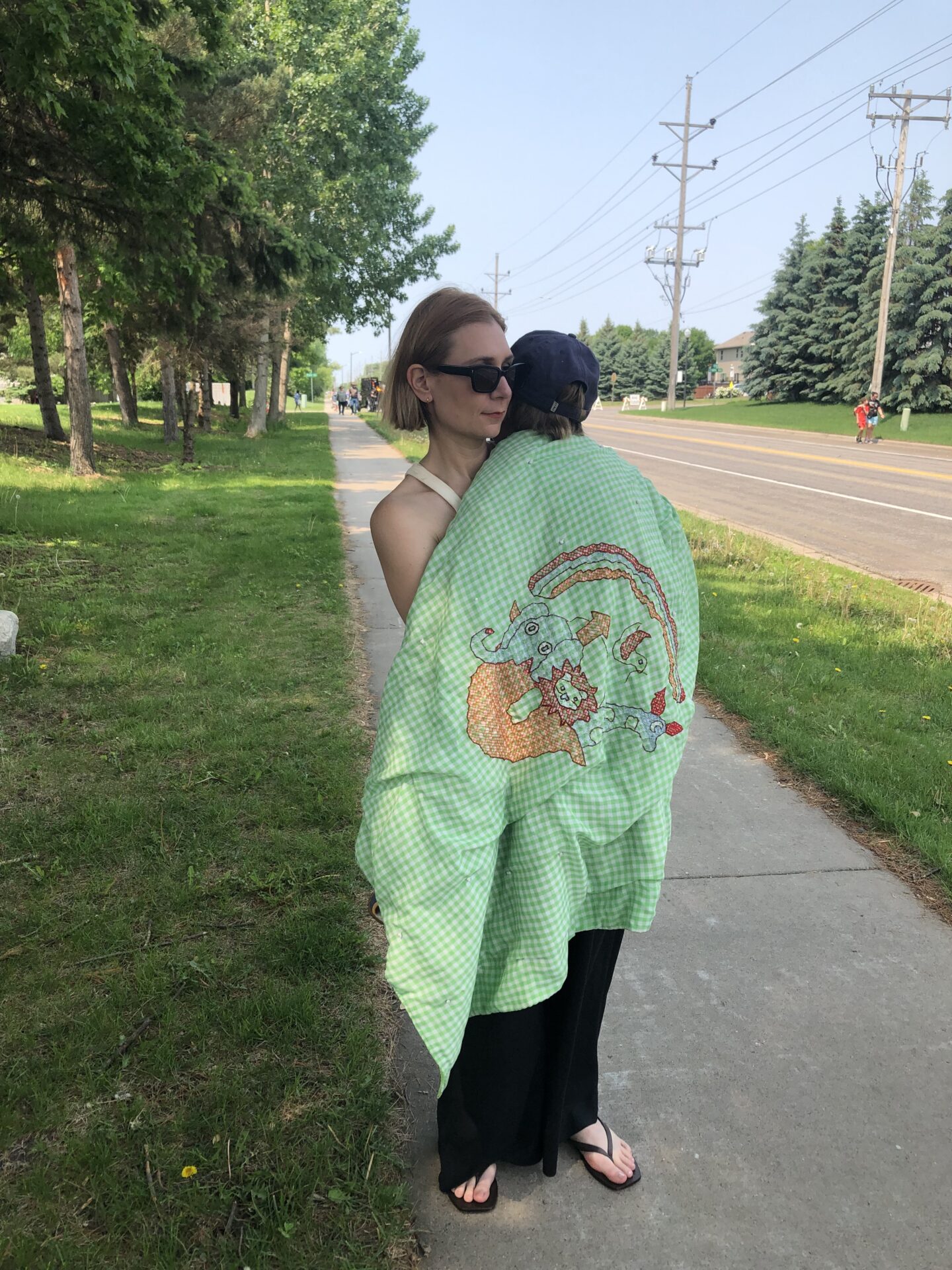 Karin Emily stands on a sidewalk and cuddles her young son in a green gingham blanket - in this blog post she talks about having a hysterectomy and what life is like with four neurodivergent children.